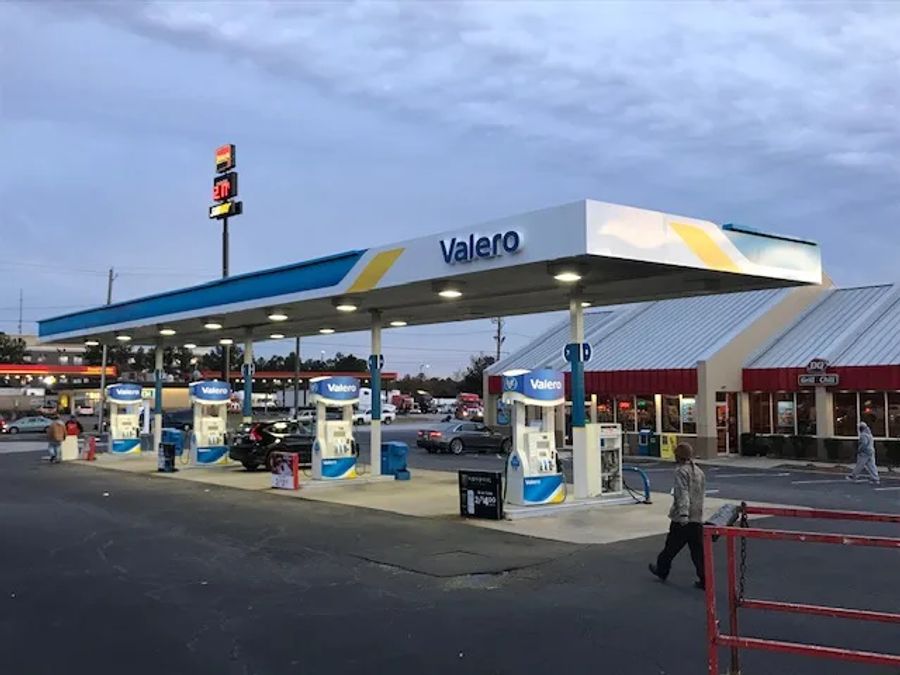 Valero canopy at dusk with lit dispensers in front of a convenience store