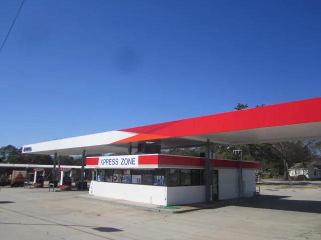 Canopy with a red and white fascia over the forecourt, a store with a matching red band