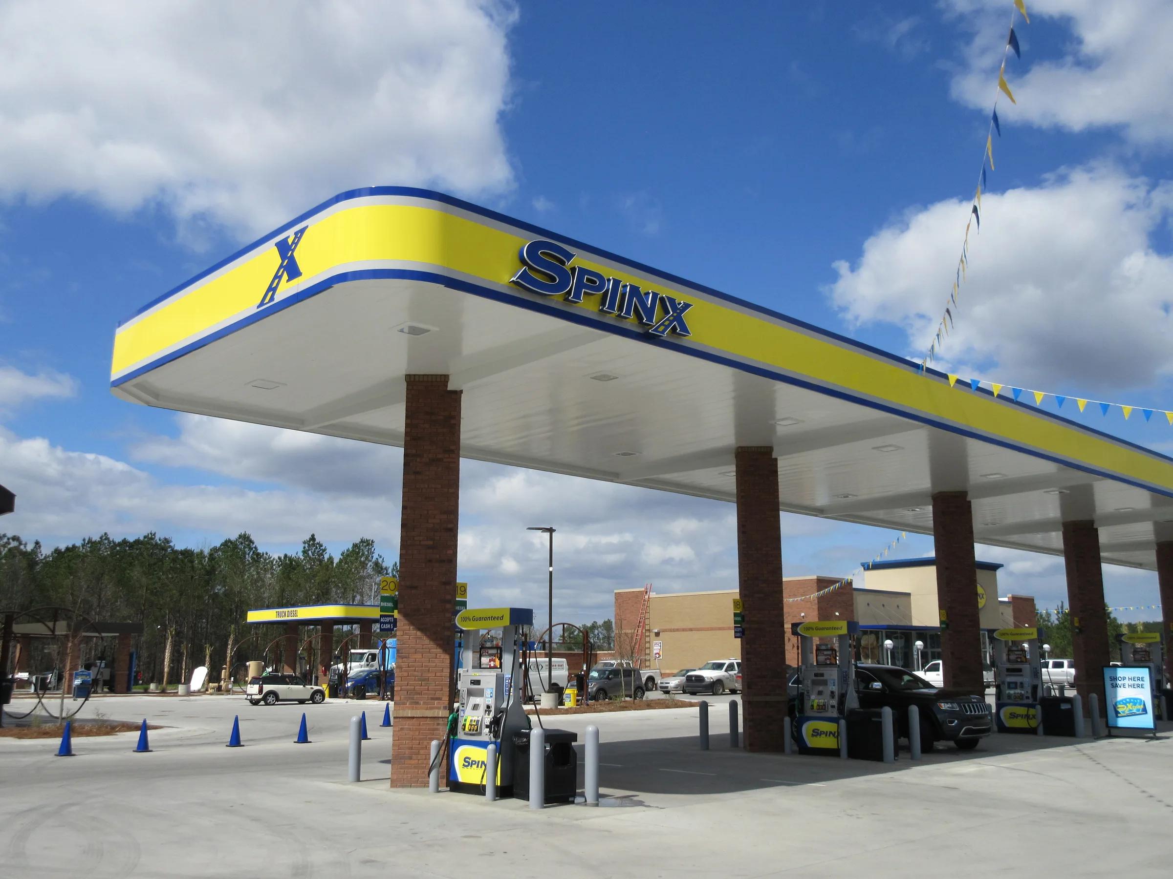 Spinx canopy with a yellow fascia on brick columns over dispensers, traffic cones on the new concrete