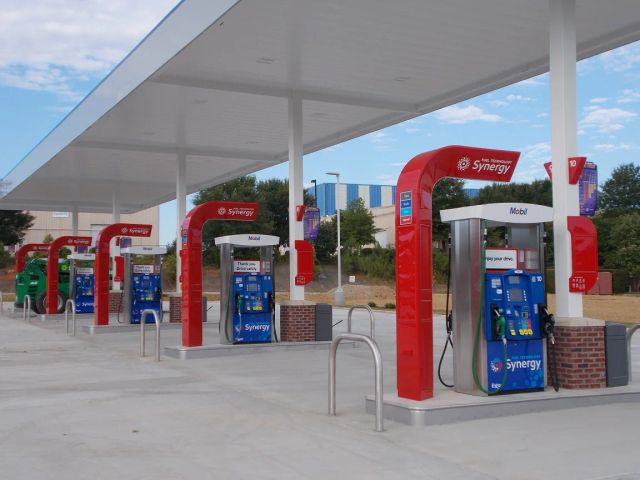 Row of Mobil dispensers with red island canopies under a white canopy deck on a new concrete forecourt