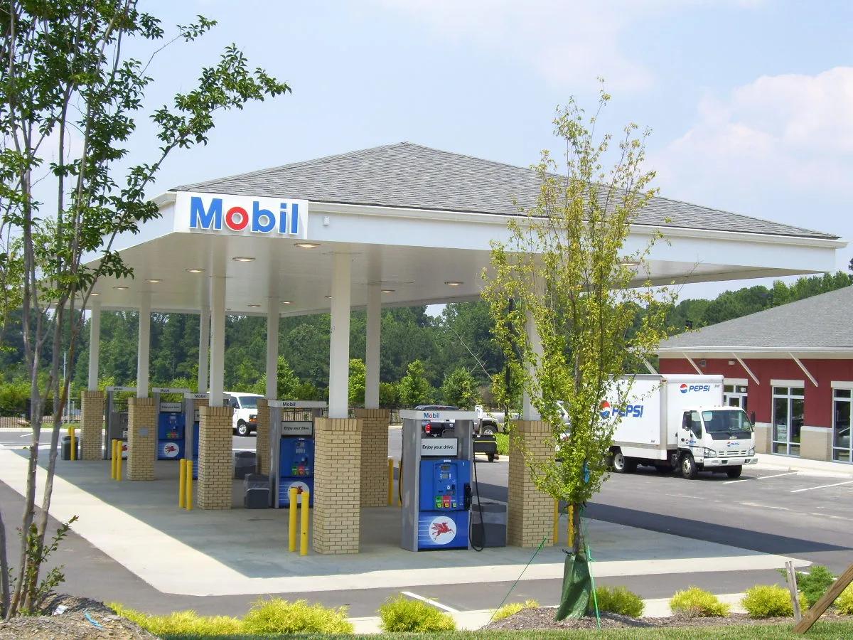 Mobil canopy with a shingled hip roof on brick columns, a new store behind it