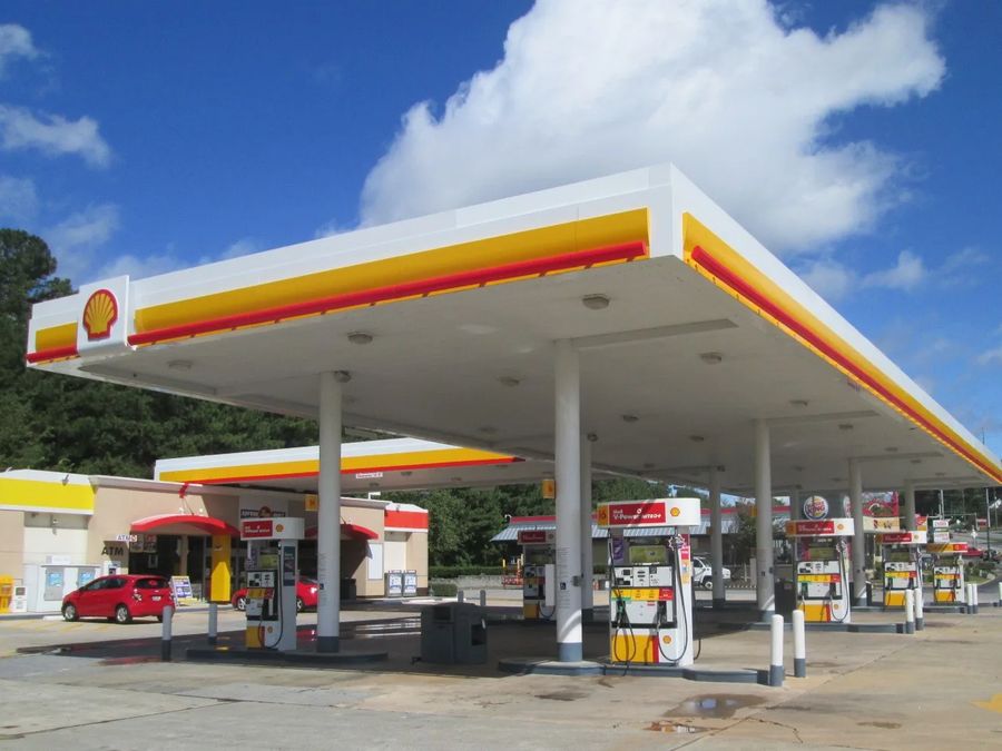 Shell canopy and dispensers under a blue sky, a convenience store behind