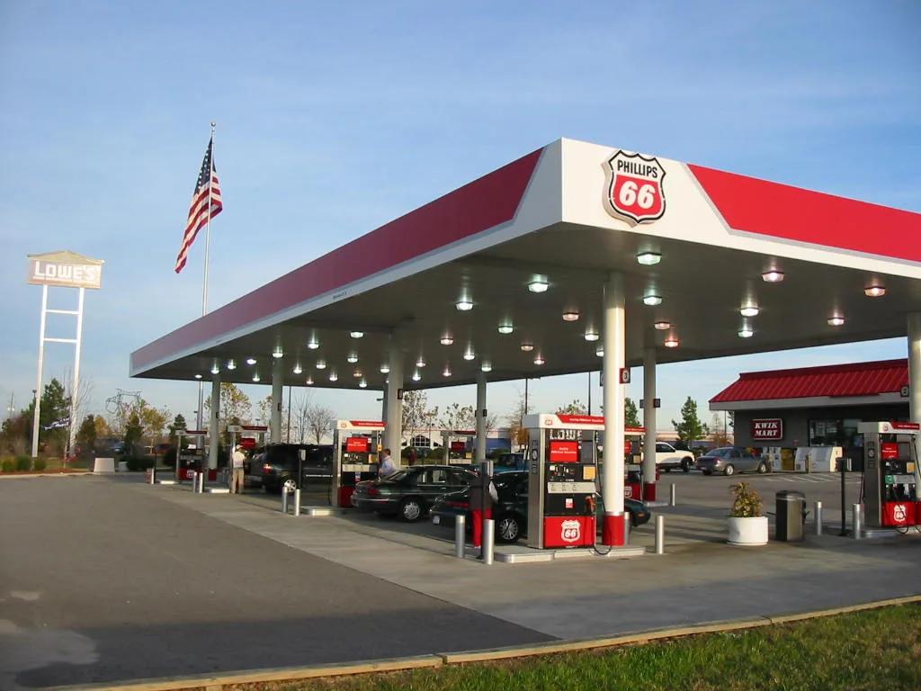 Phillips 66 canopy with a red fascia and shield sign over a long row of dispensers at dusk