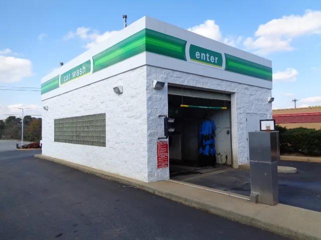 Car wash building with green fascia bands and an enter sign over the bay door