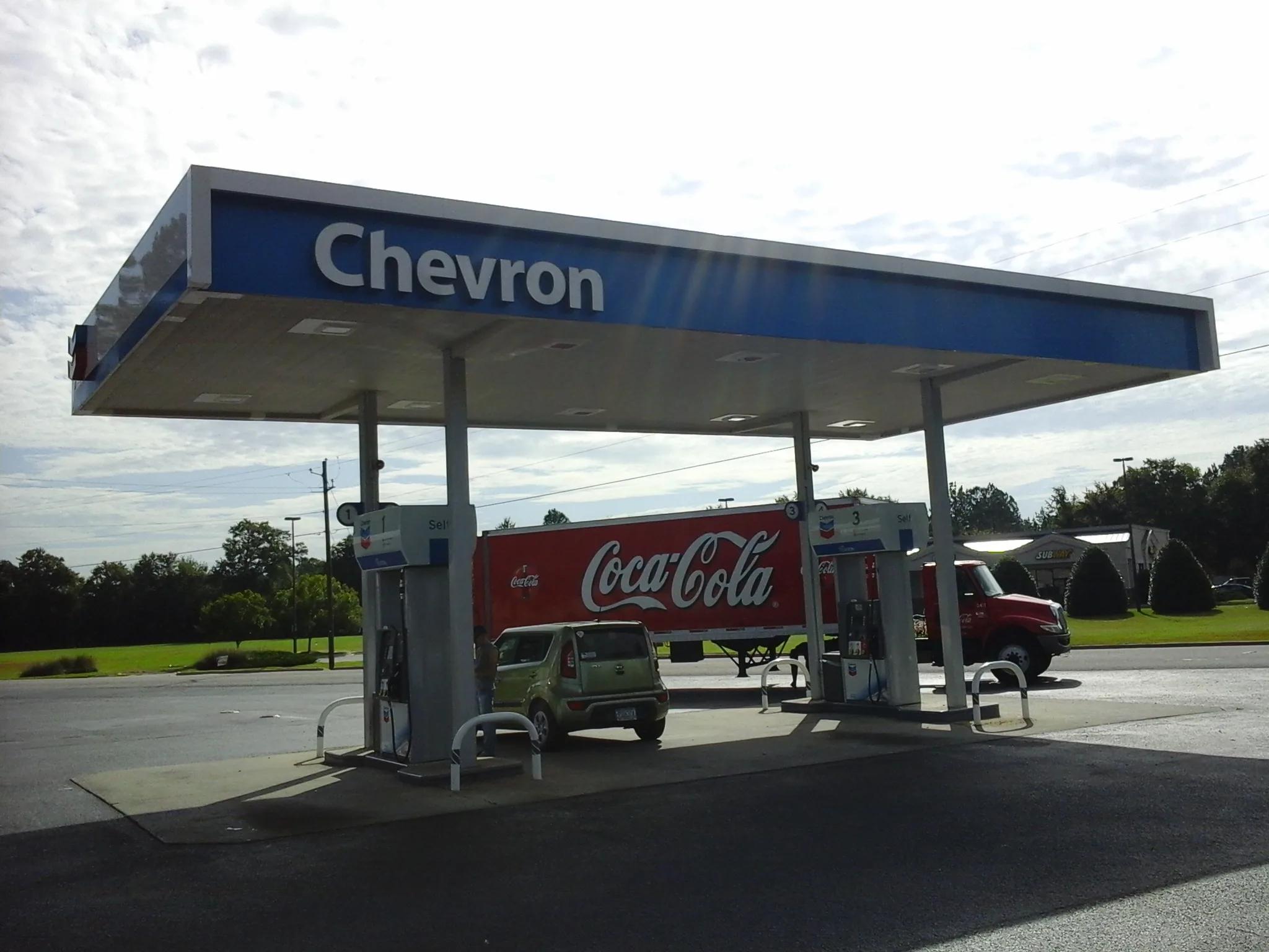 Chevron canopy with a blue fascia over two dispensers, a tractor-trailer parked beyond