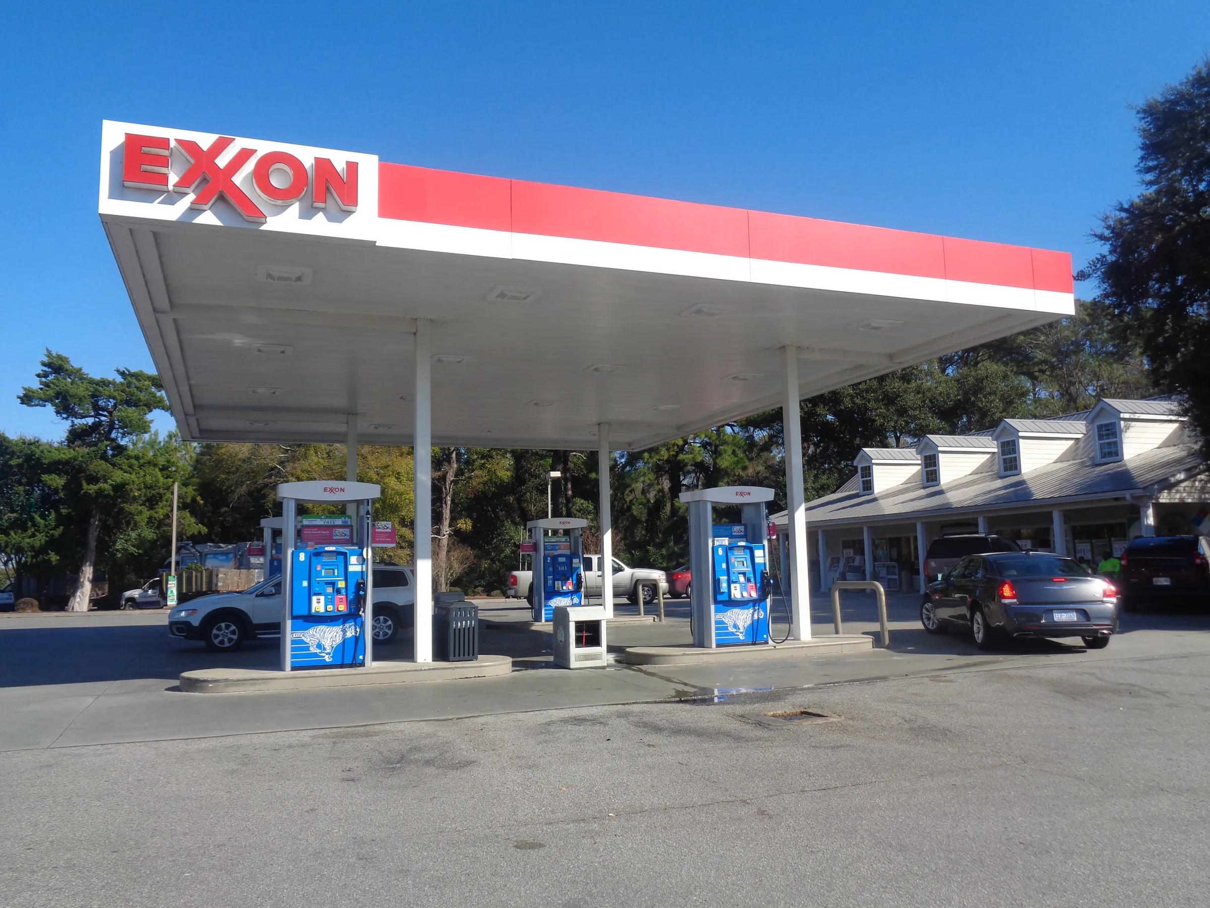 Exxon canopy with a red fascia over a row of blue dispensers in front of a store