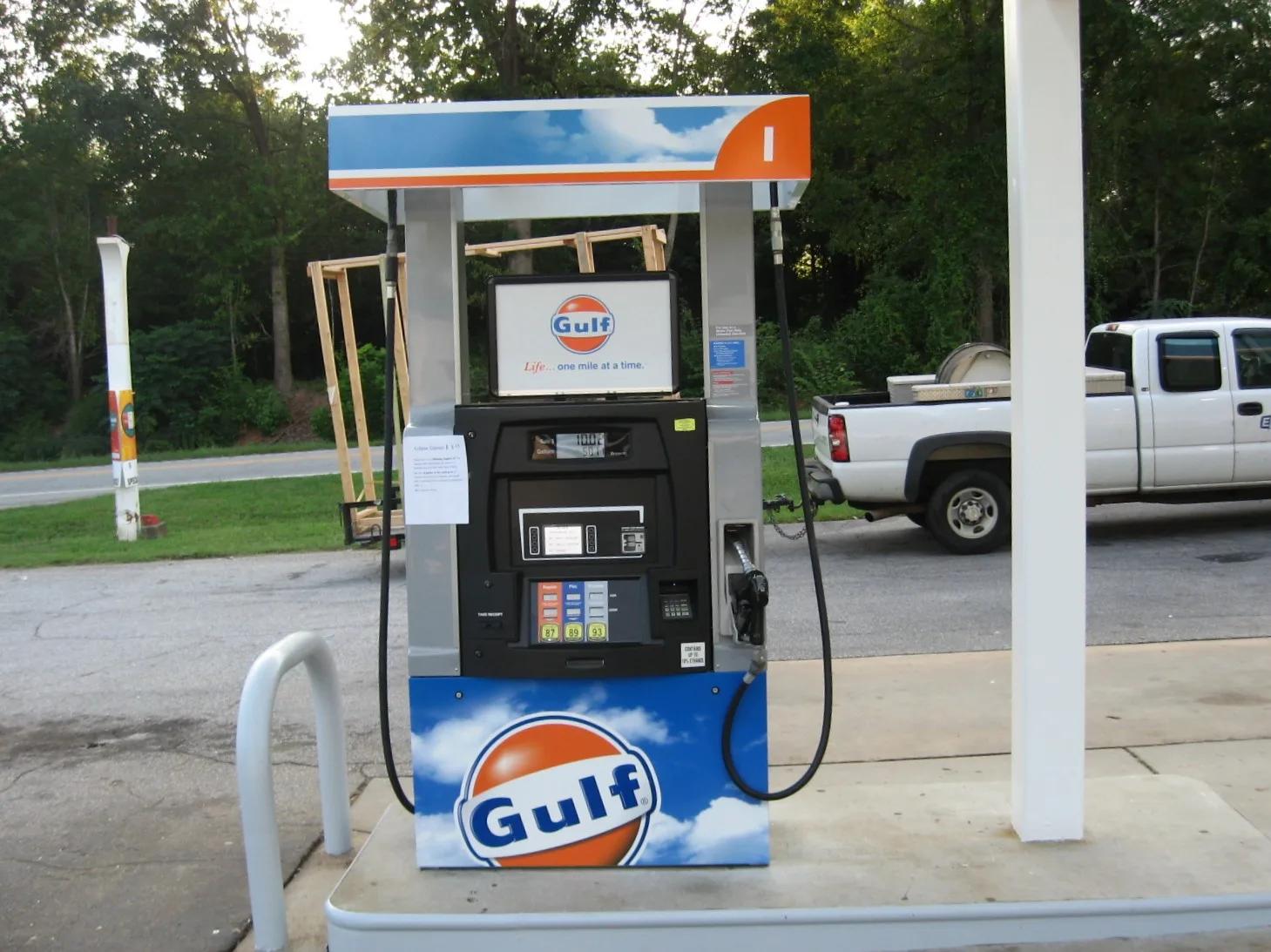 Gulf dispenser with orange and blue graphics on an island, a pickup truck behind