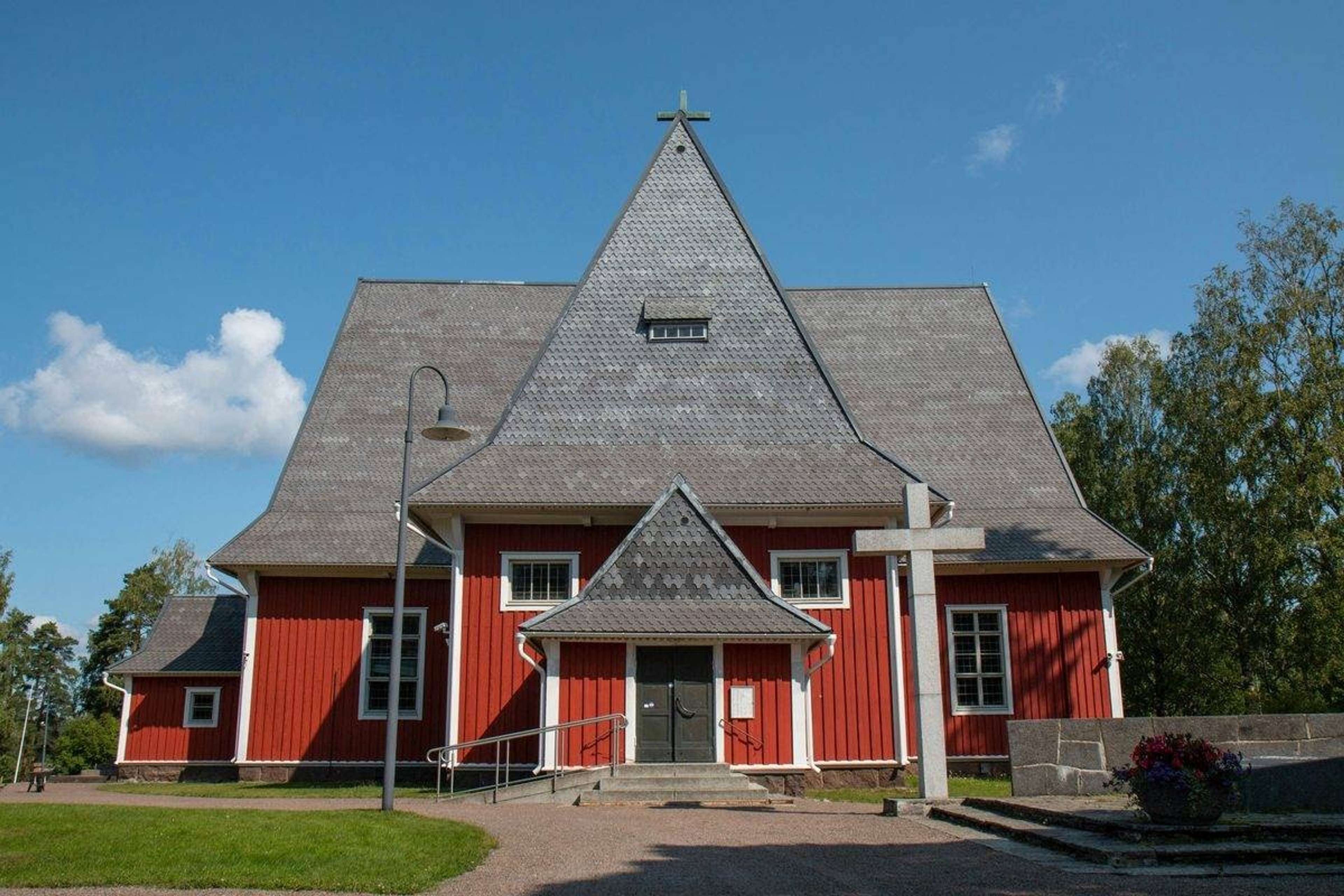 Punainen puukirkko korkealla harmaalla katolla aurinkoisena kesäpäivänä