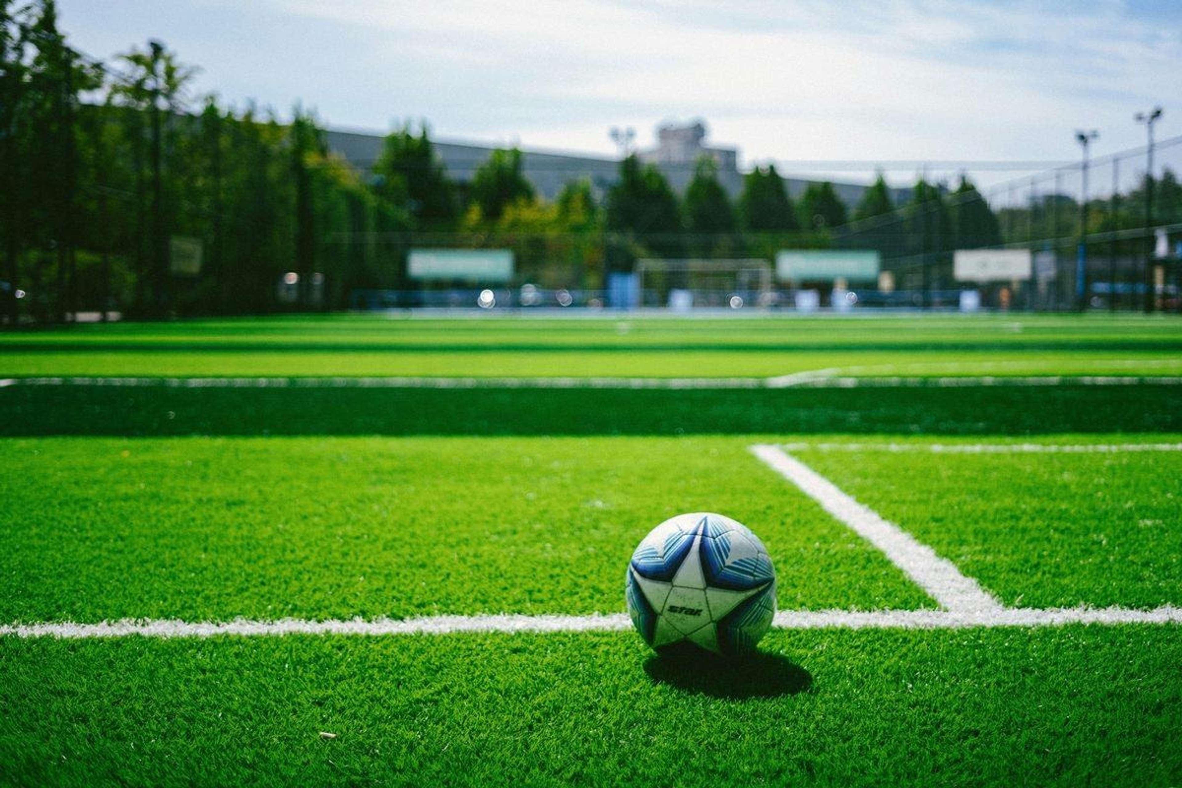 Fotboll på en konstgräsplan med målet i bakgrunden