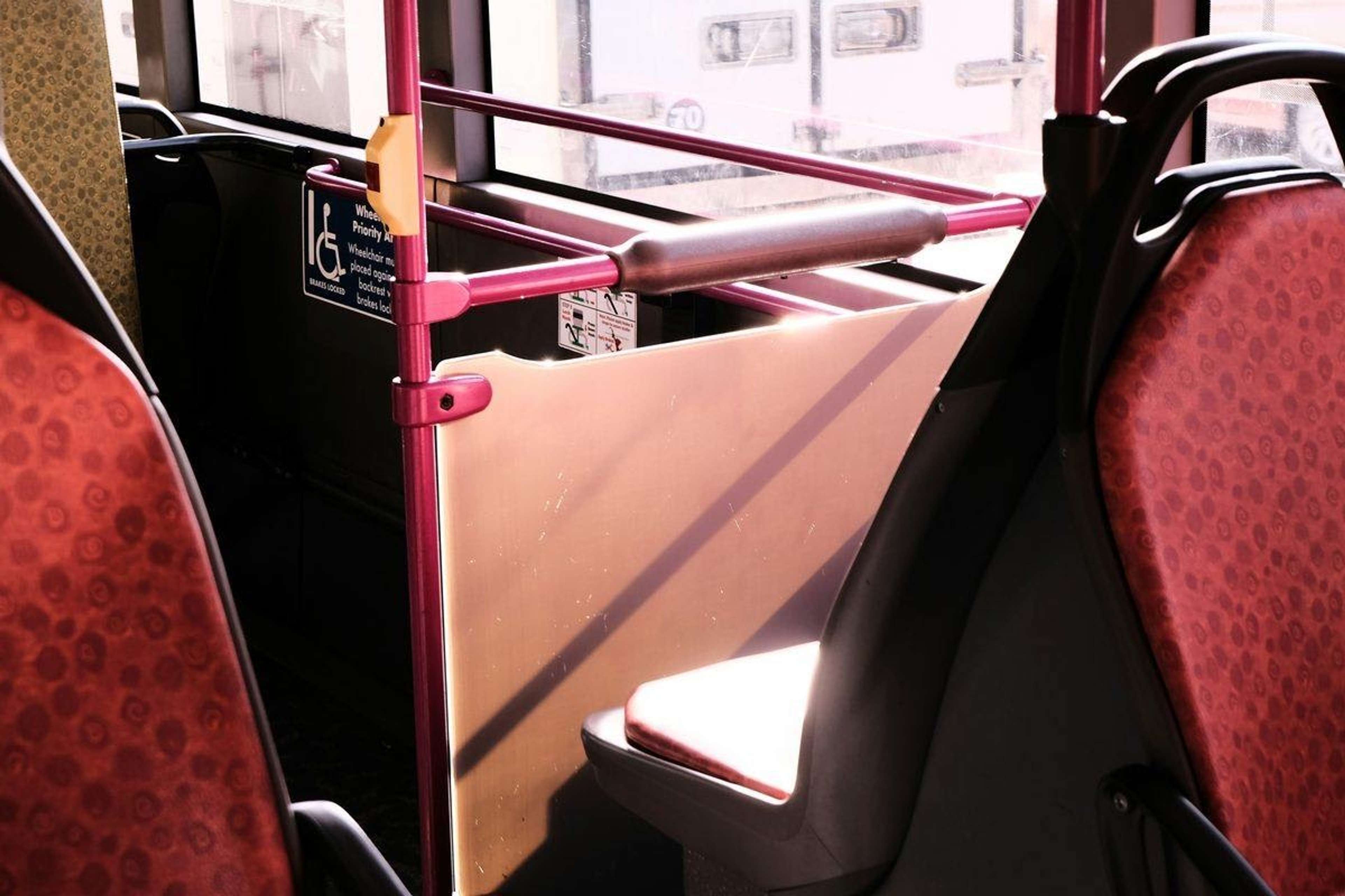 Rullstolsplats i en buss med fällbart säte, ledstång och rullstolsskylt