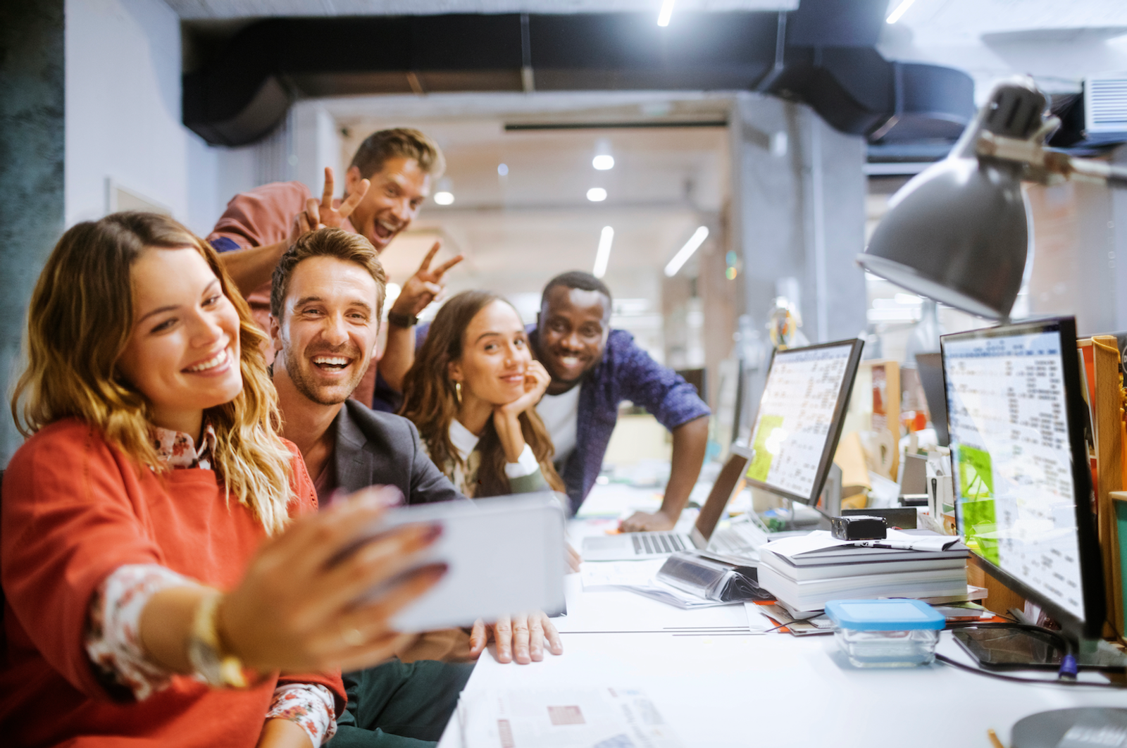 Coworkers smiling and posing for a photo at their desk.