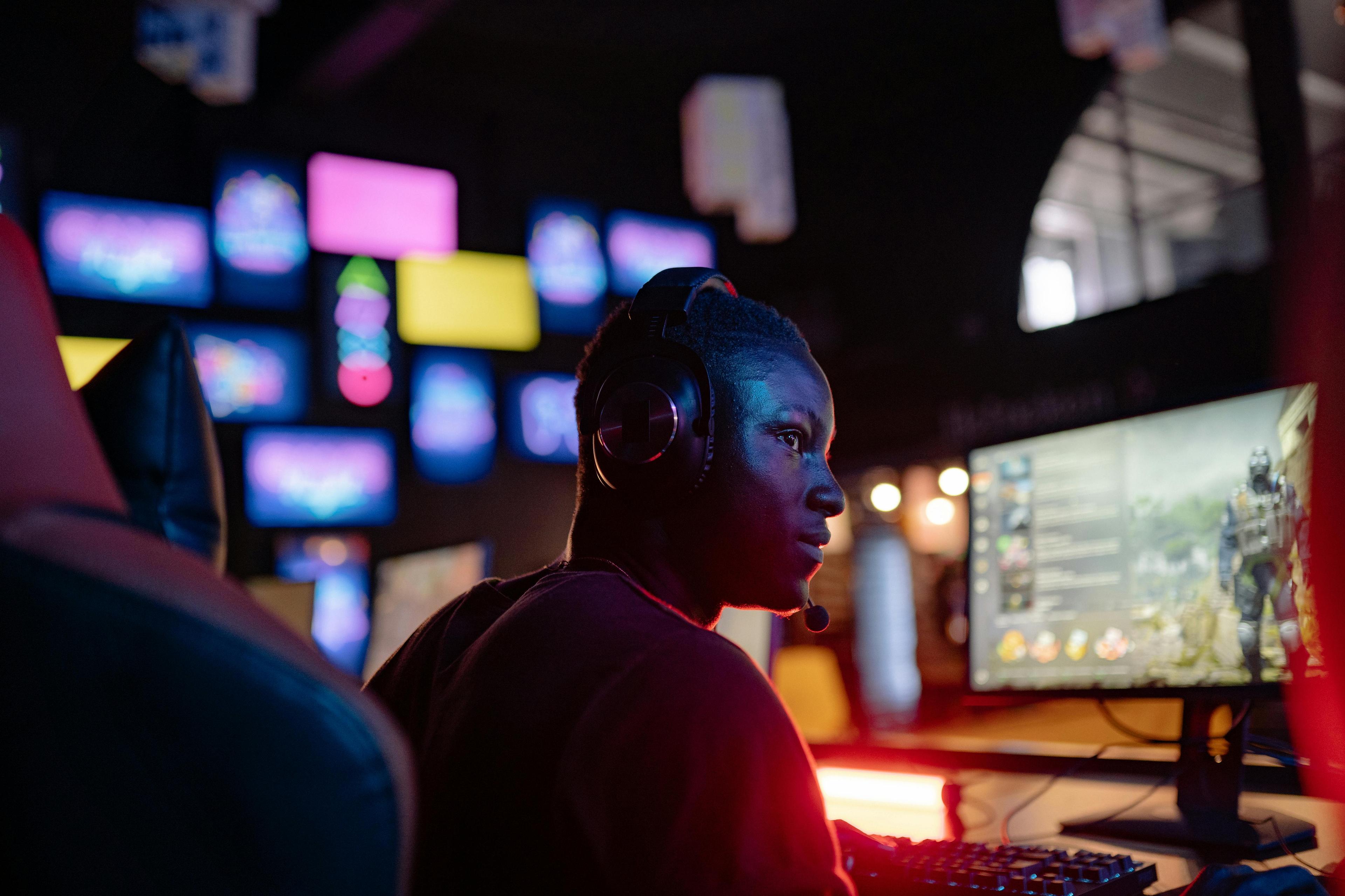 young man wearing a headset is sitting in front of a PC game featuring an armored player