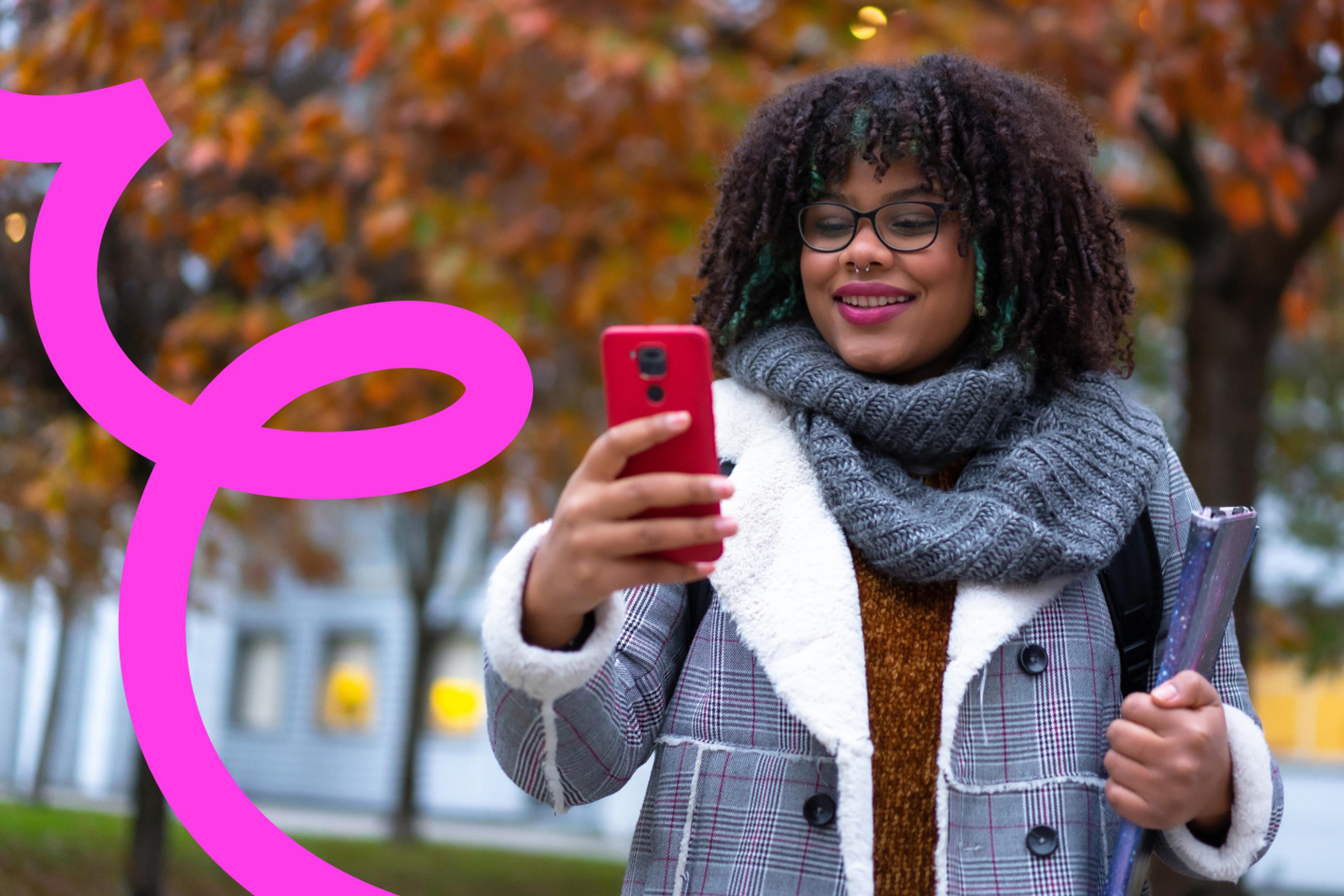 Woman looking at smart phone with autumnal trees in background