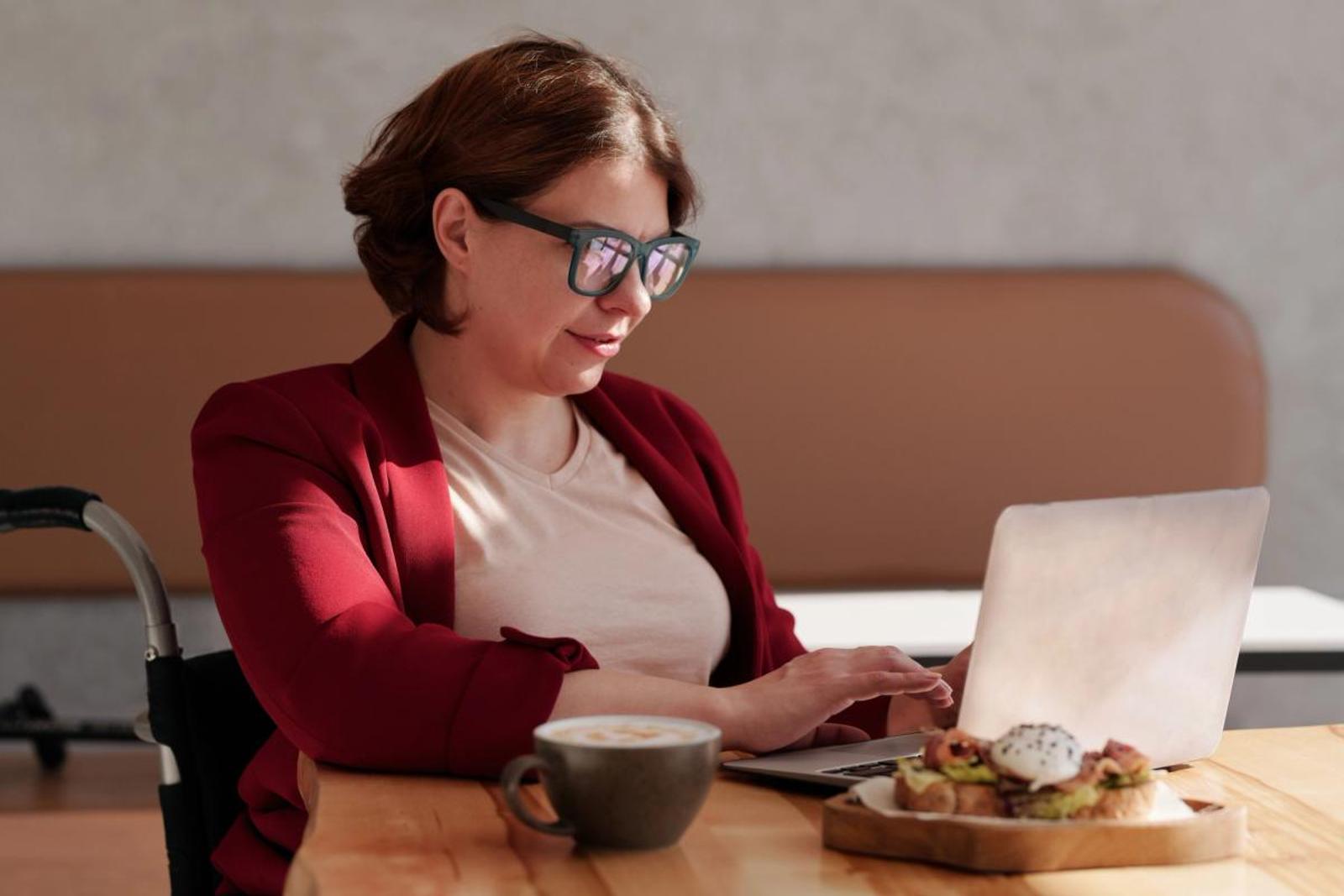 a woman seated at a table on her laptop