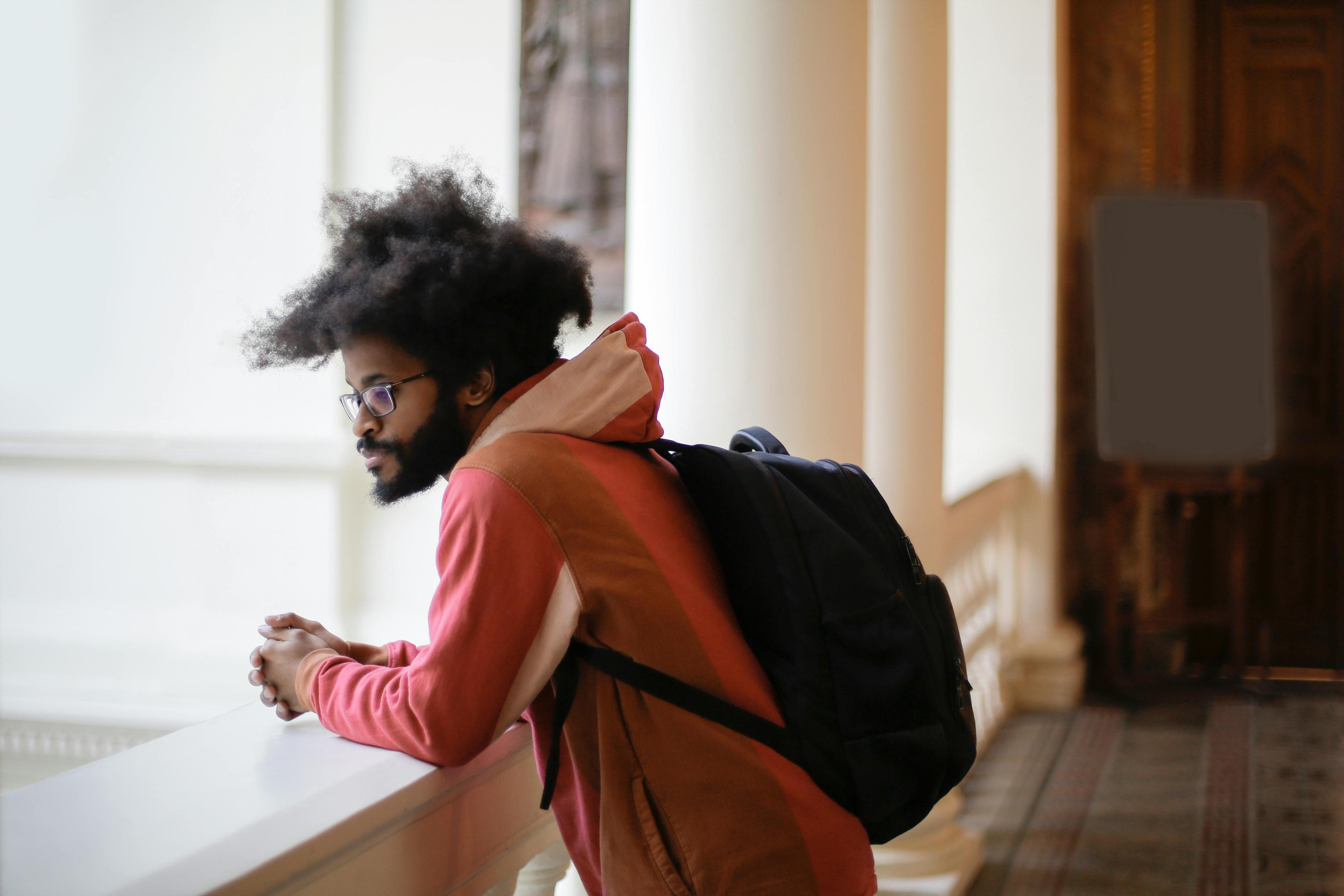 Young man wearing backpack in campus hallway