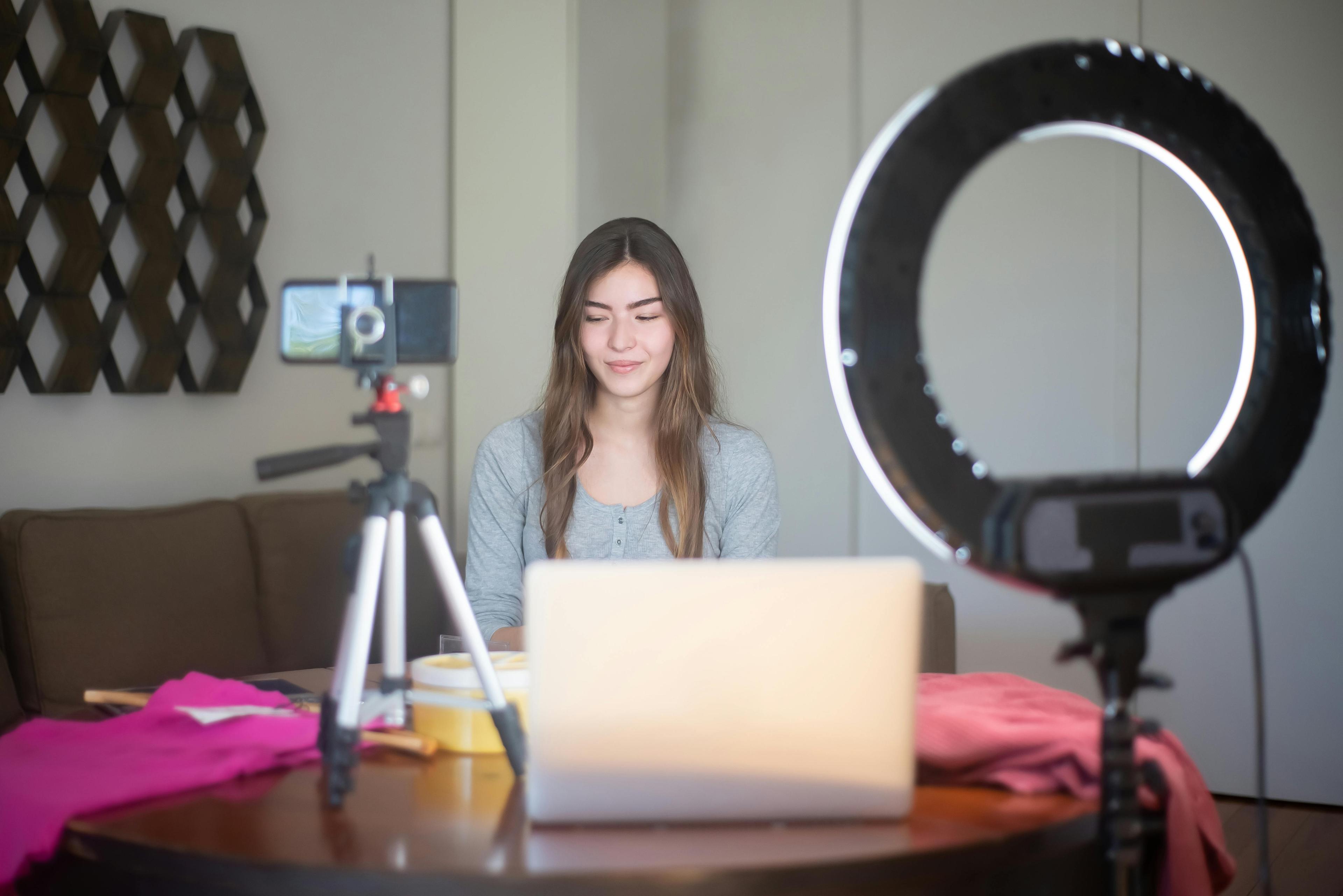 Young woman recording video with laptop and ring light