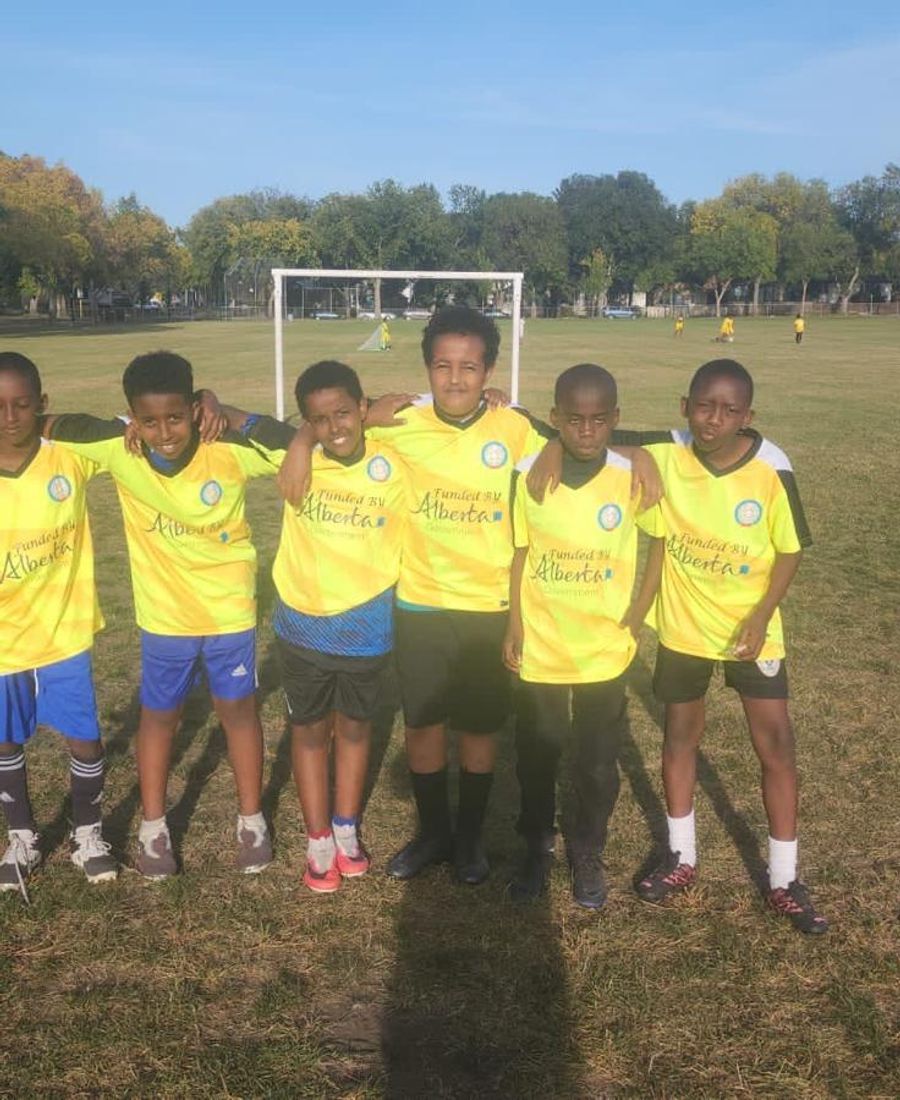 Six boys in yellow SISSA youth soccer jerseys pose together on a grass soccer field.