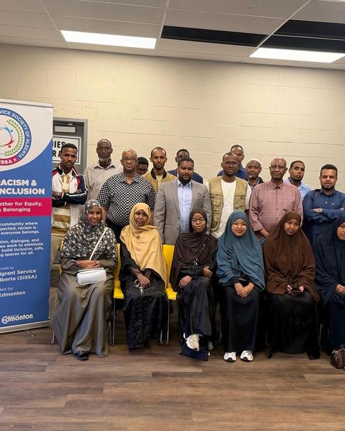 Participants gather for a group photo beside the SISSA Anti-Racism & Social Inclusion banner and a Canadian flag.