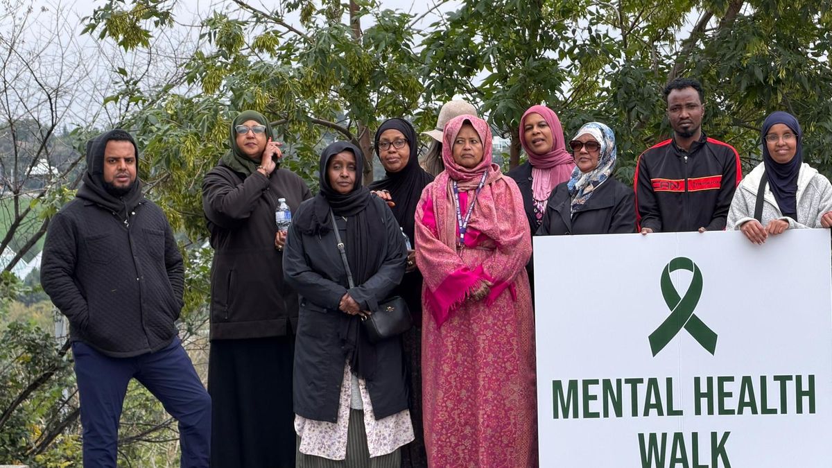 Community members pose outdoors holding a Mental Health Walk Edmonton sign.
