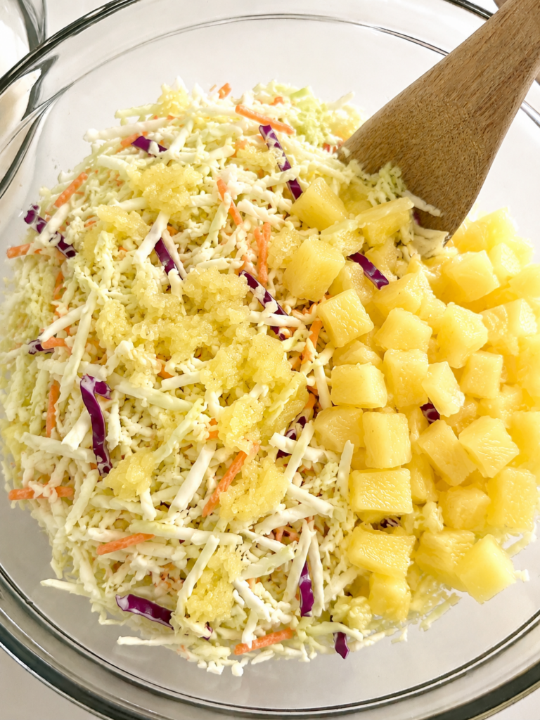 Shredded cabbage and pineapple combined in a mixing bowl