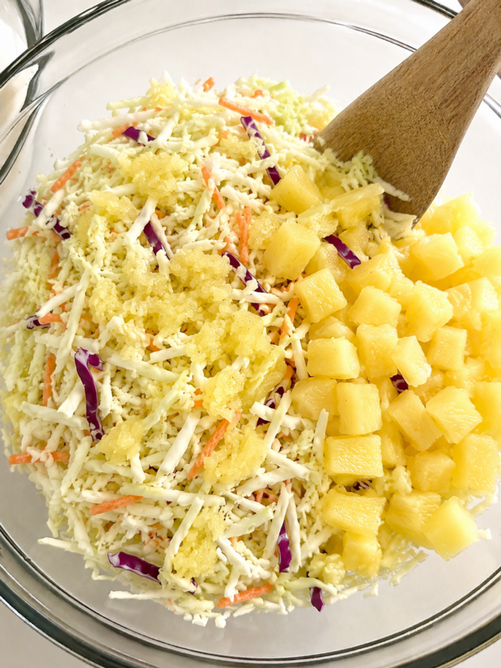 Shredded cabbage and pineapple combined in a mixing bowl