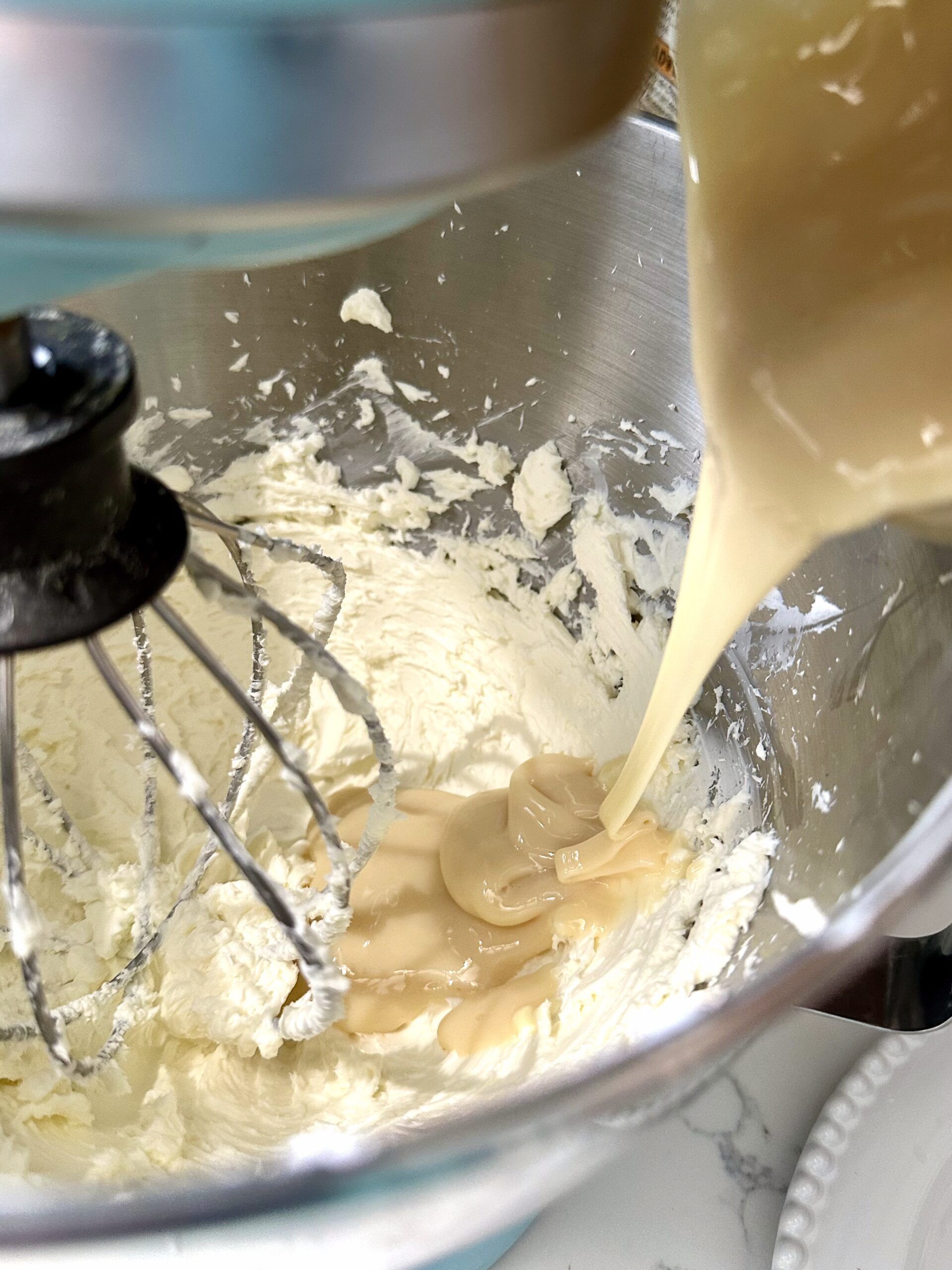 Sweetened condensed milk being mixed into cream cheese