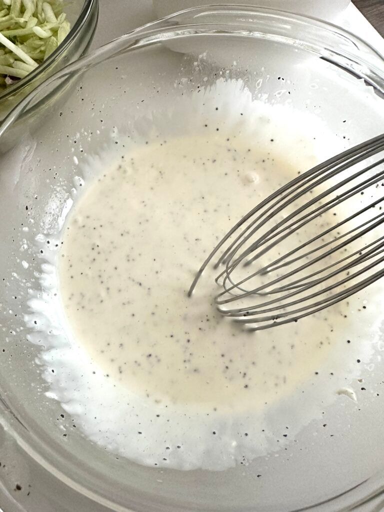 Creamy pineapple coleslaw dressing being whisked