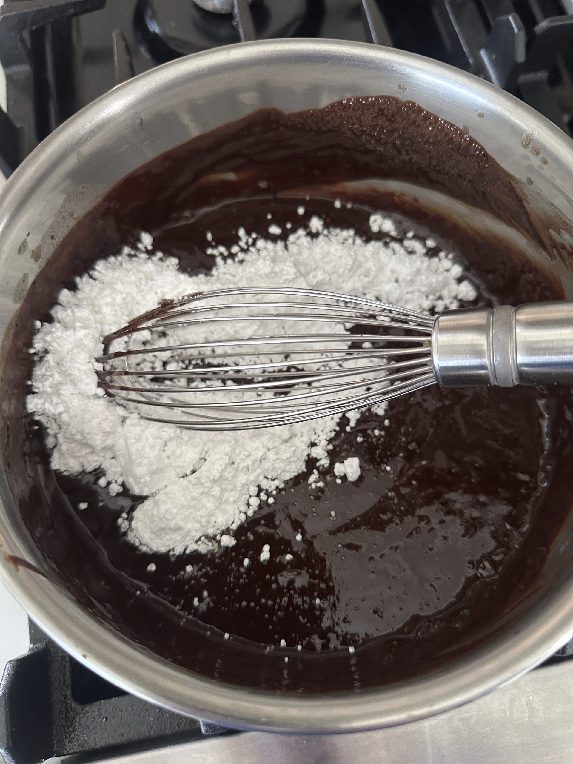 Powdered sugar being whisked into melted chocolate icing