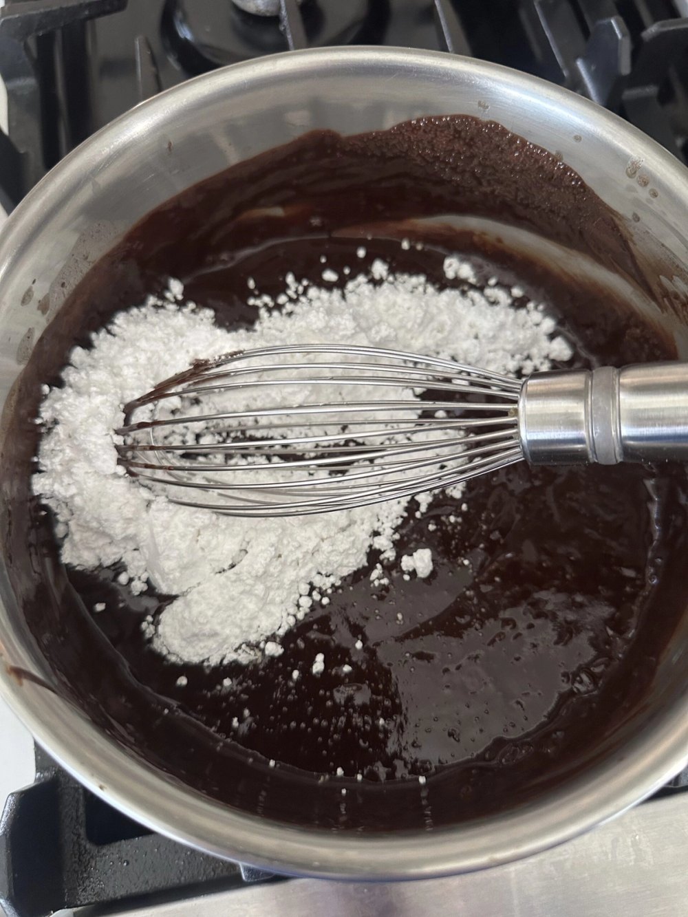 Powdered sugar being whisked into melted chocolate icing