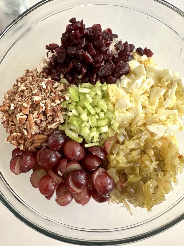 Chicken, boiled eggs, celery, and sweet pickles combined in a mixing bowl