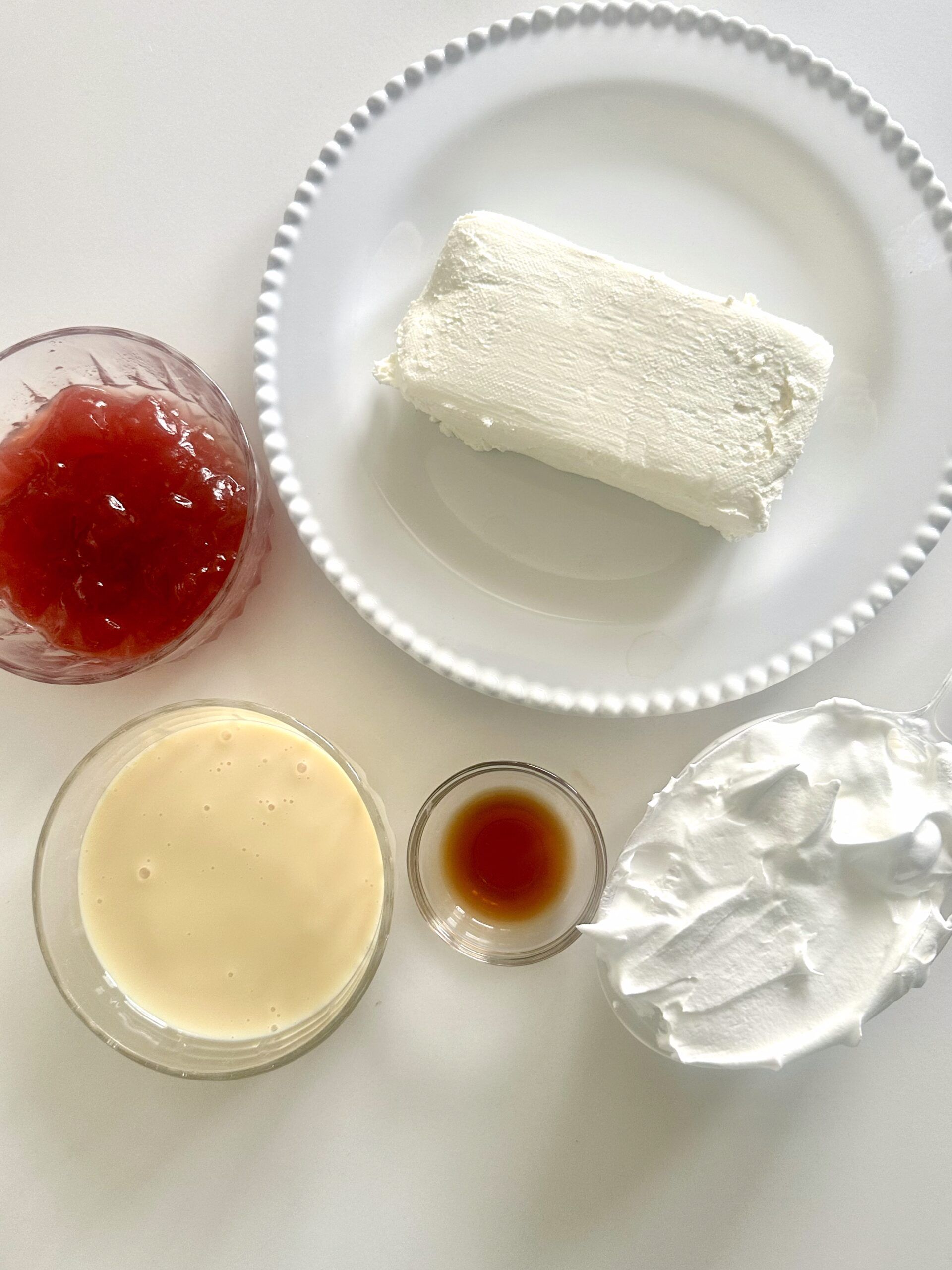 Ingredients for strawberry cheesecake dip arranged on a counter