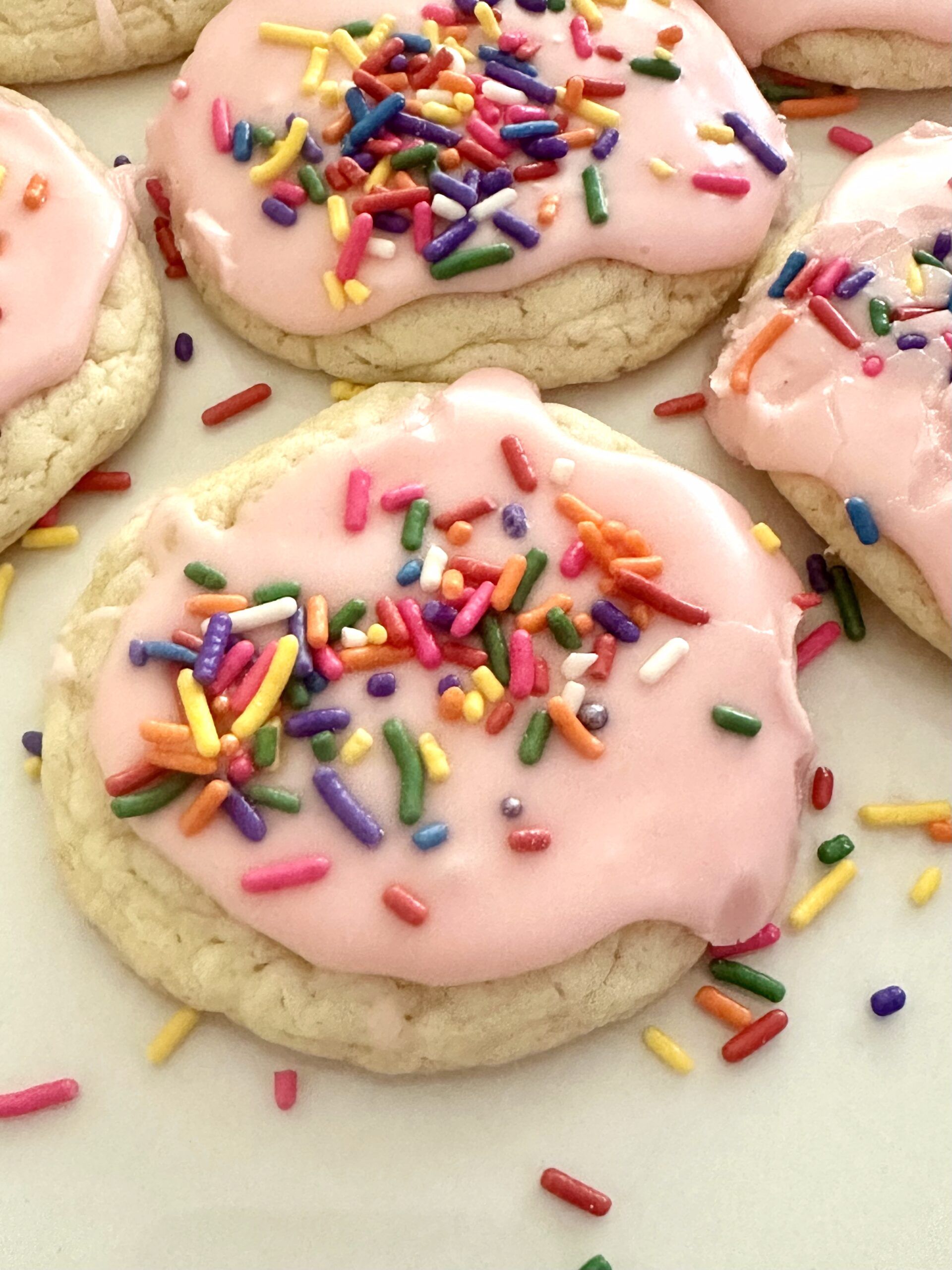 Soft white cake mix cookies topped with pink vanilla glaze and sprinkles