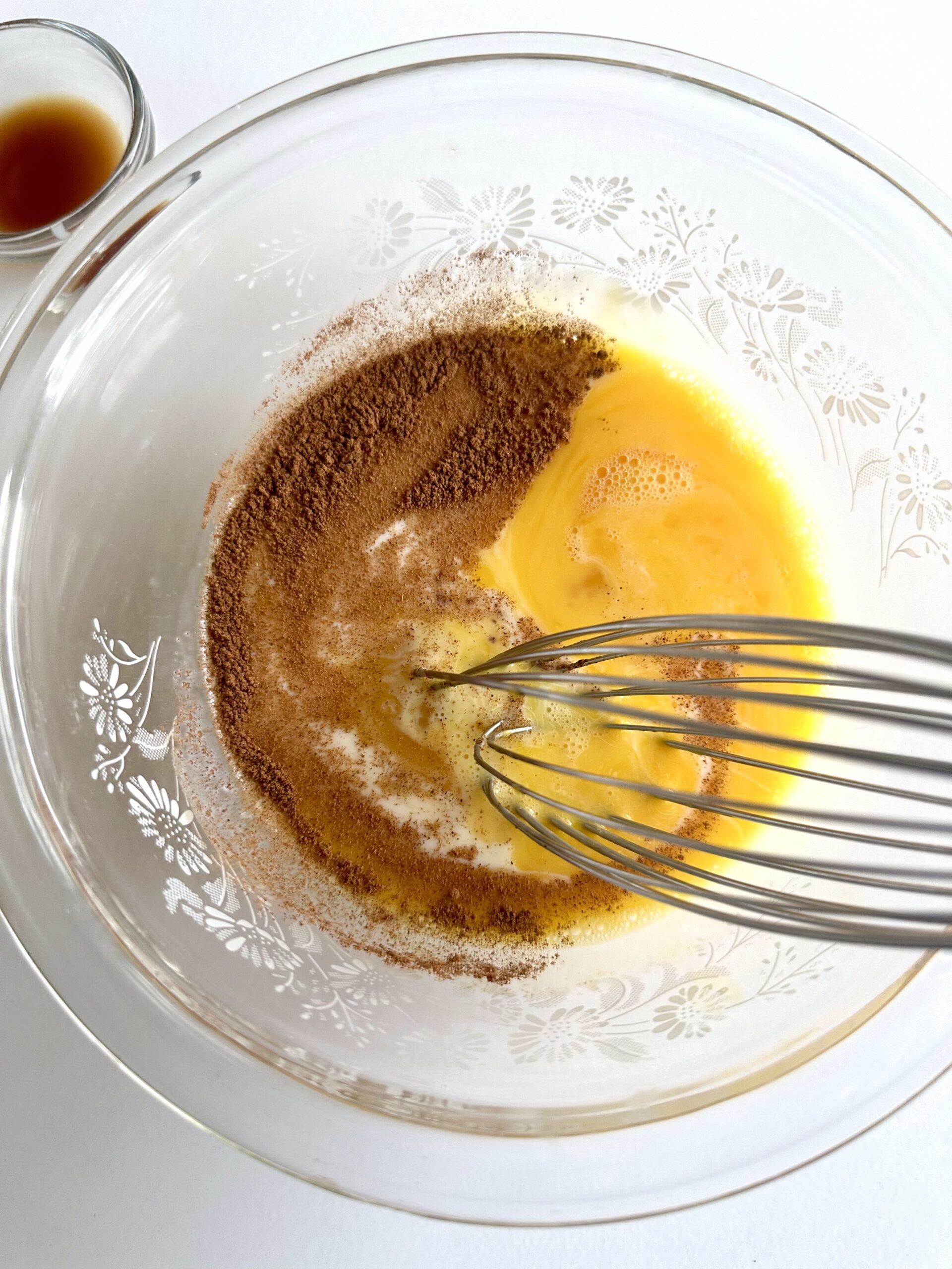 A thick slice of brioche being dipped in cinnamon custard