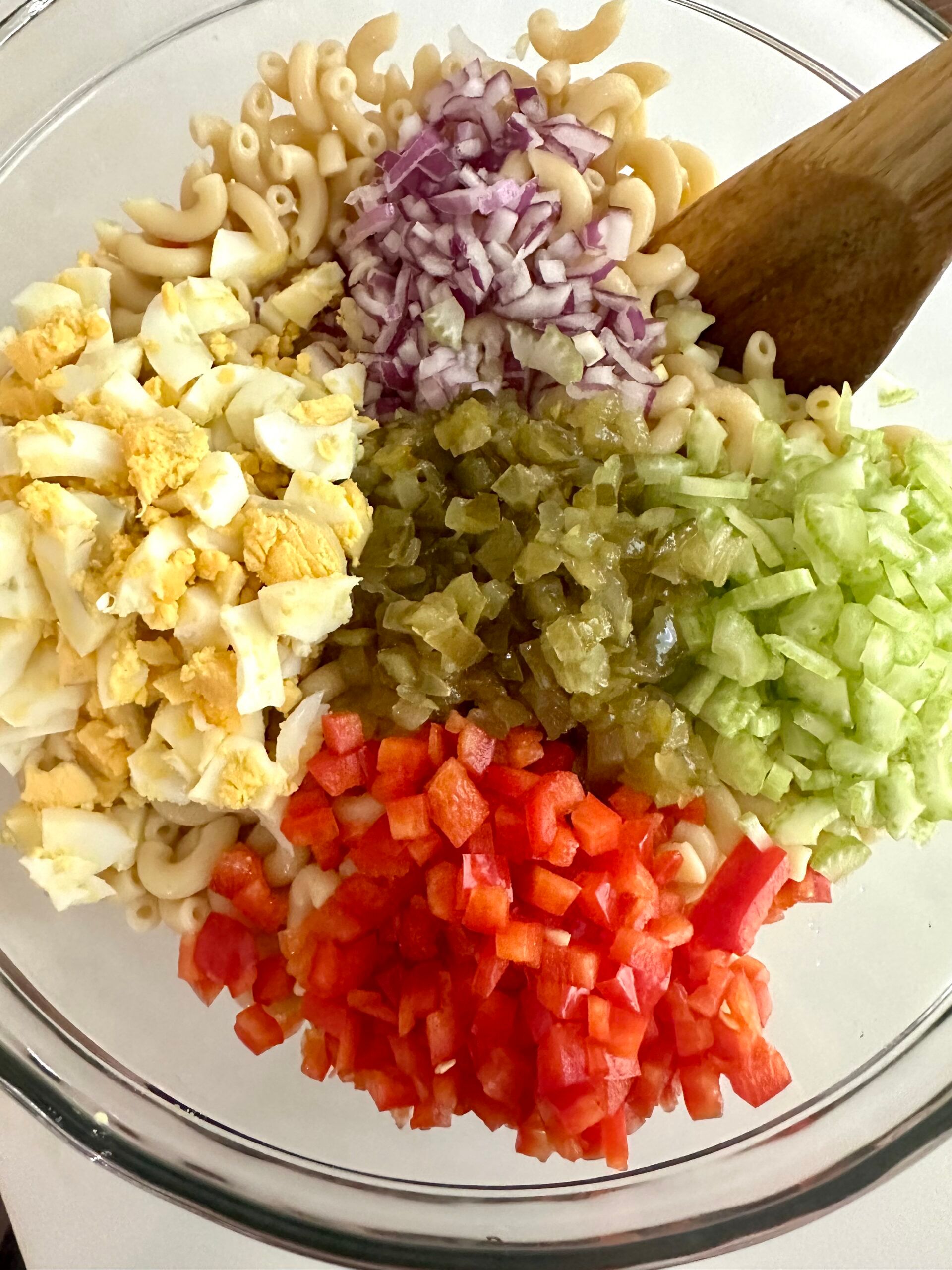 Cooked macaroni with chopped eggs, celery, red onion, pickles, and red bell pepper