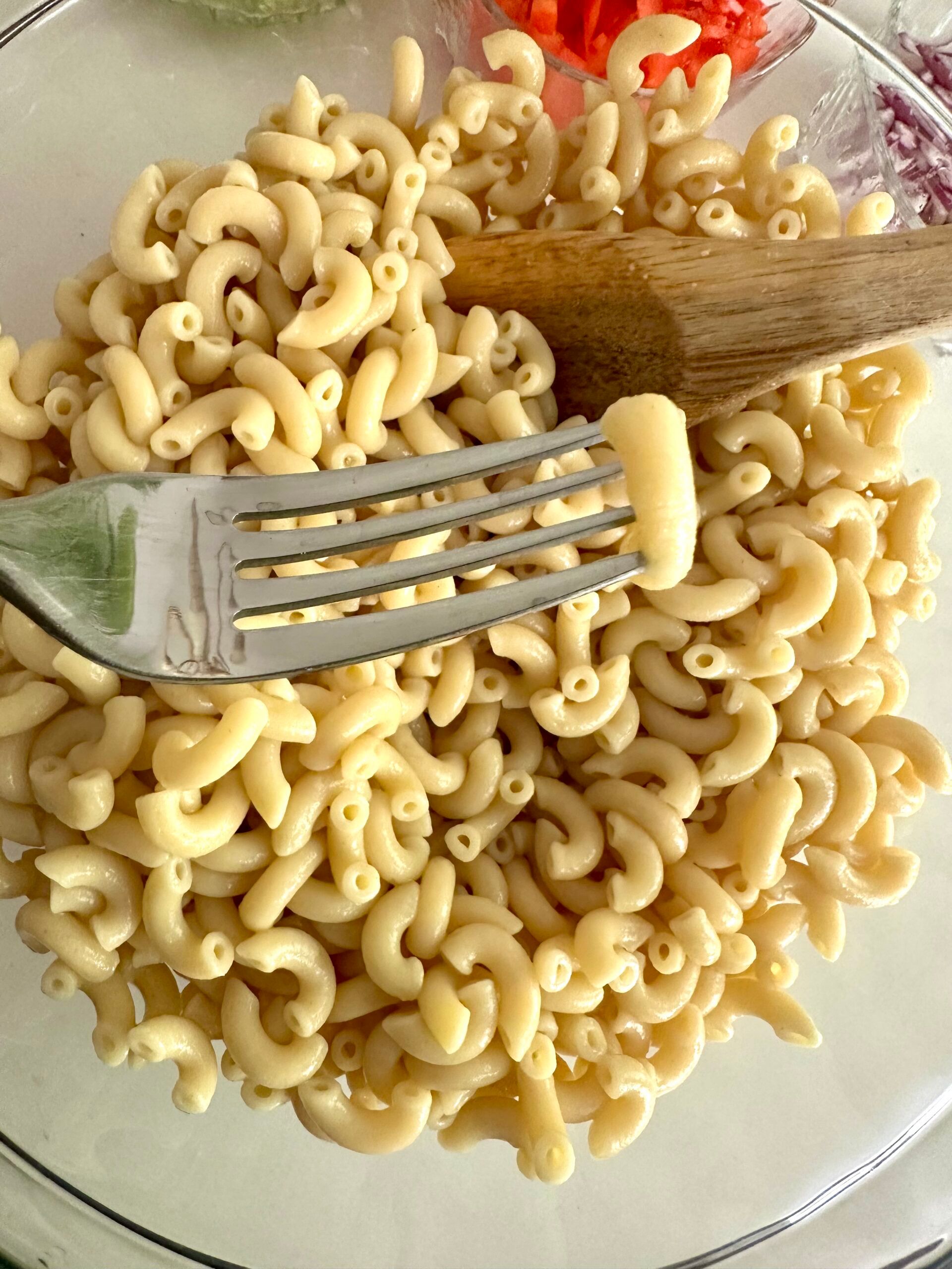 Cooked elbow macaroni cooling in a large glass bowl