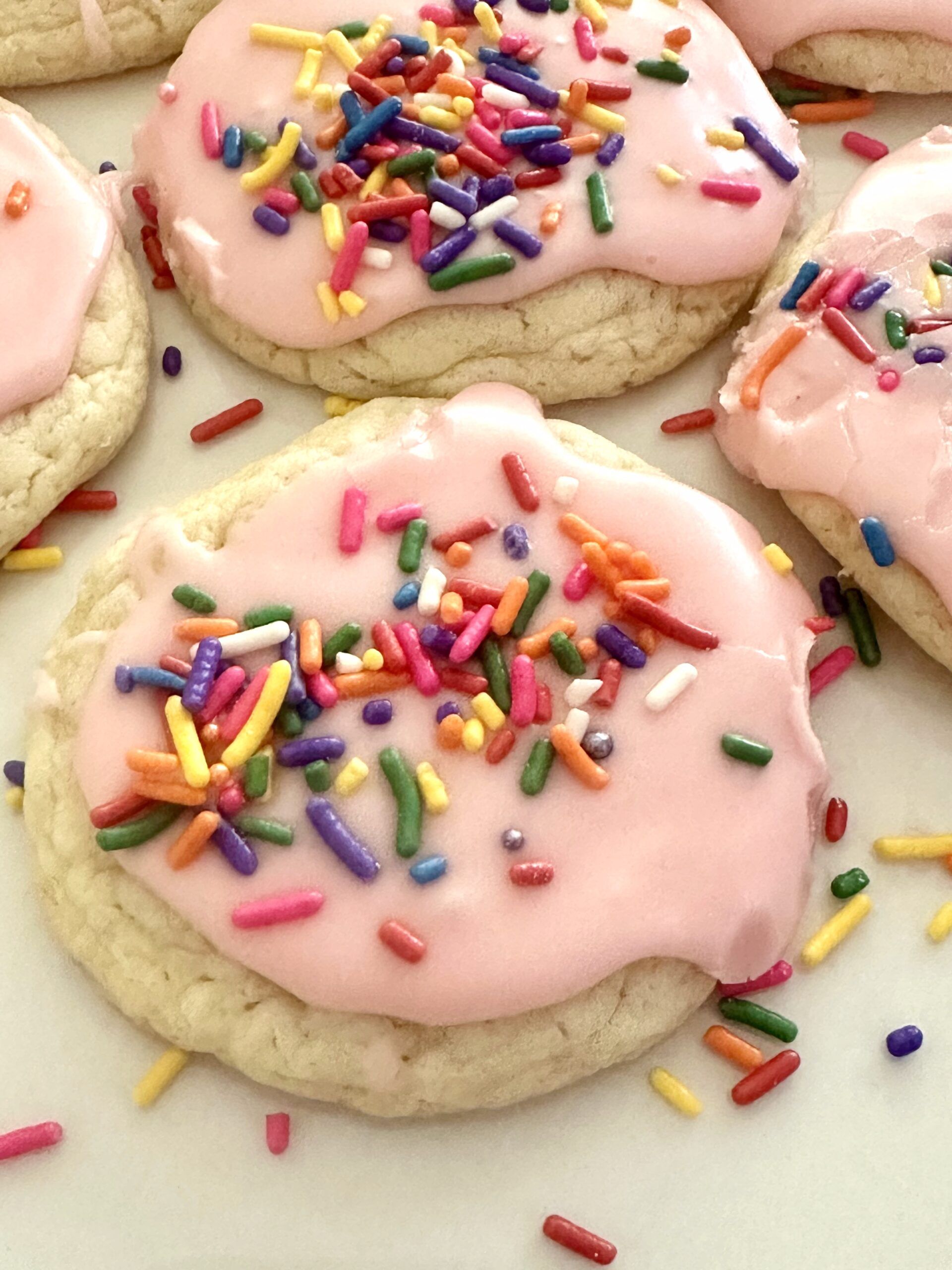 Soft cake mix cookies with pink vanilla glaze and colorful sprinkles