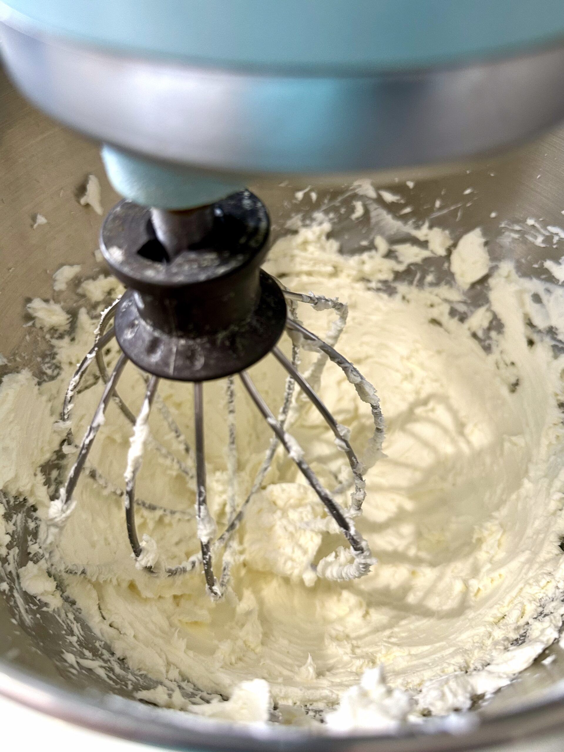 Softened cream cheese being beaten until smooth