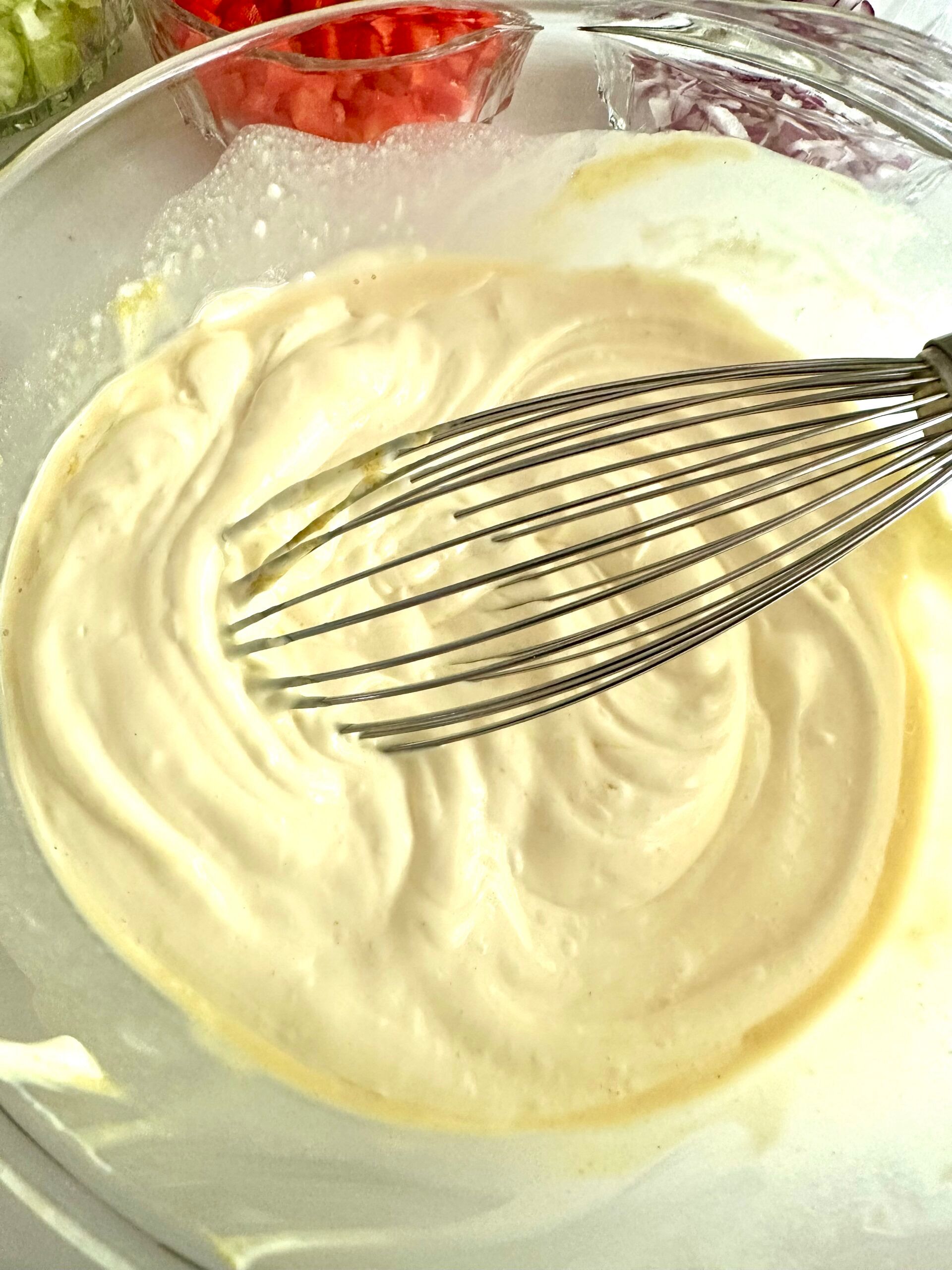 Creamy macaroni salad dressing with a whisk