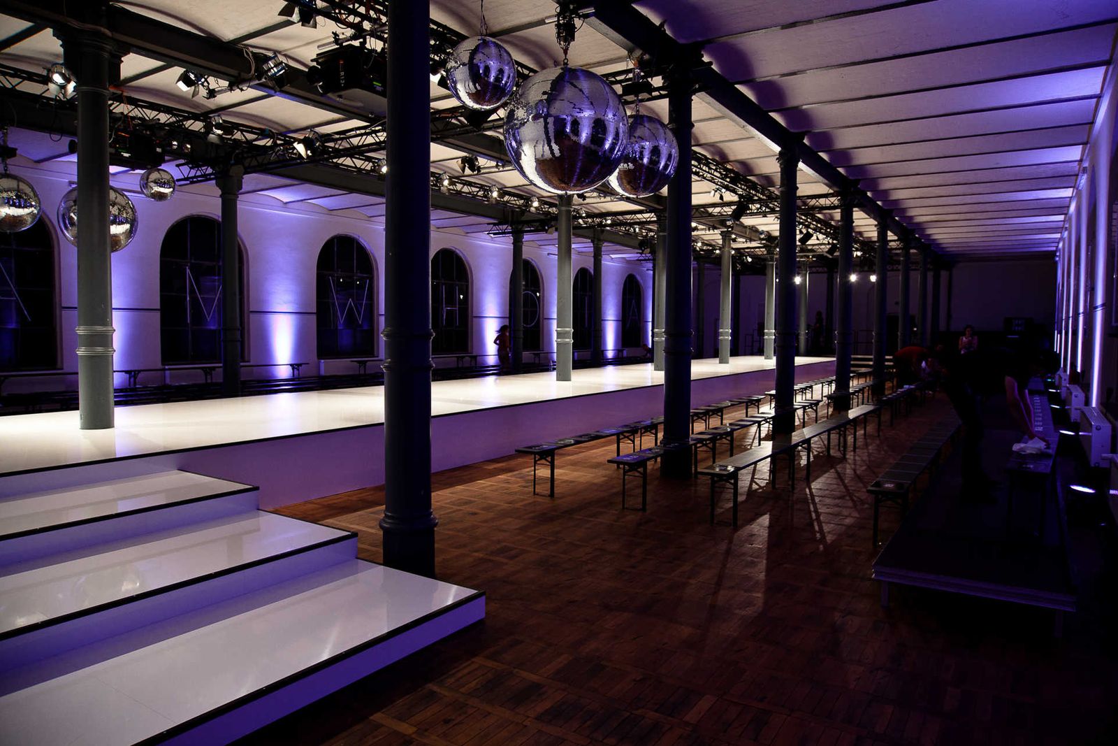 Long hall with white catwalk and large disco balls.