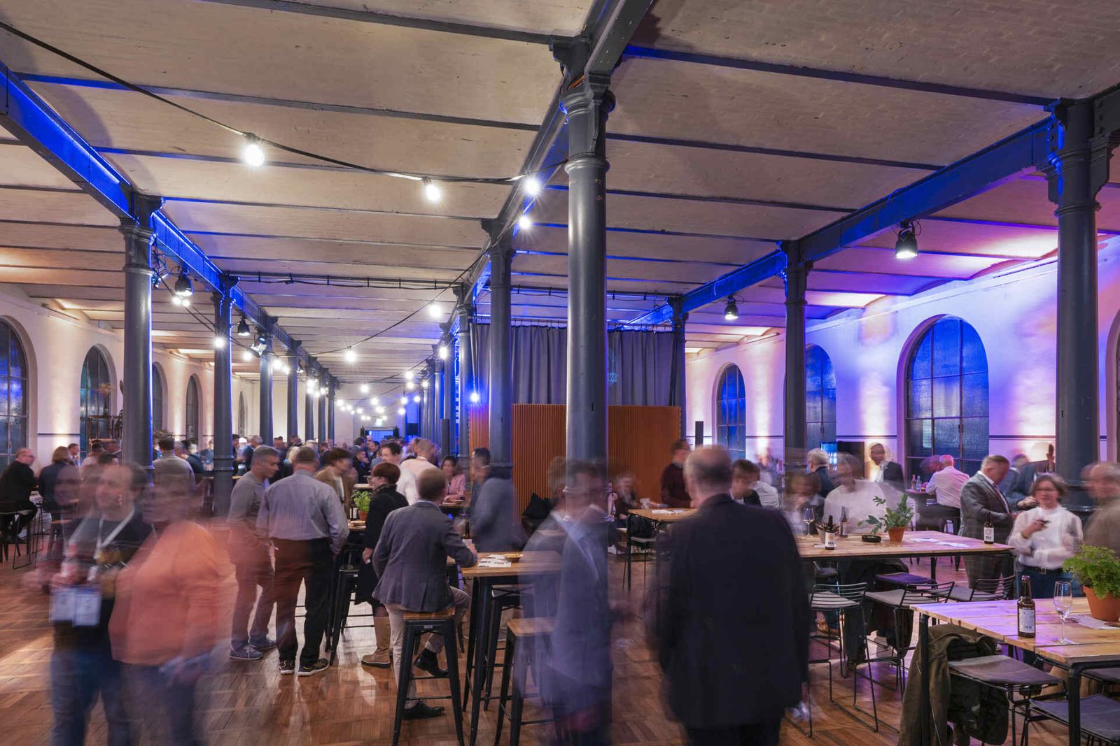 Eventsaal mit atmosphärischer Beleuchtung und Menschen während einer Veranstaltung.