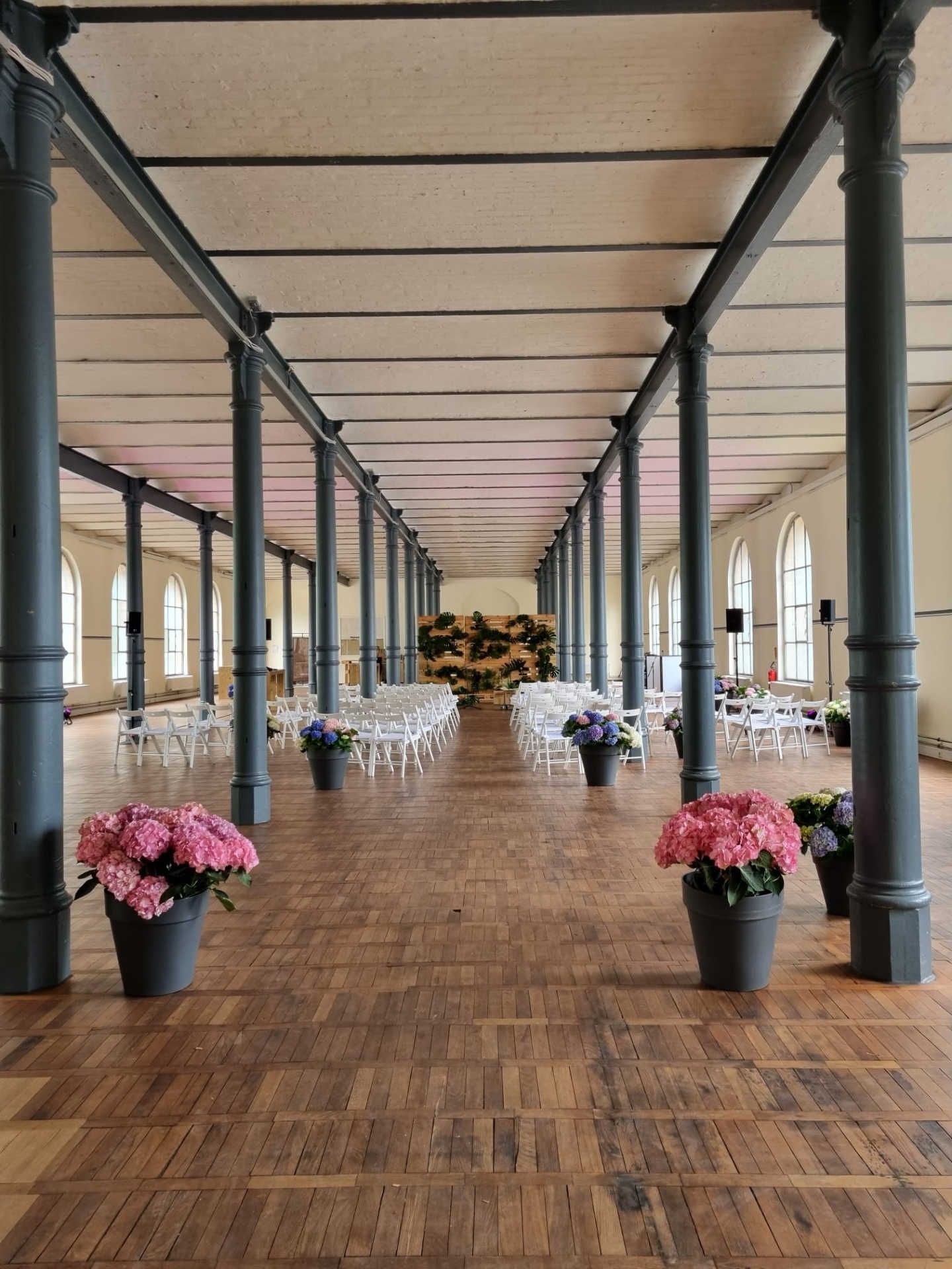 Großer Saal mit Zeremonie-Bestuhlung, Säulen und Blumendekoration.