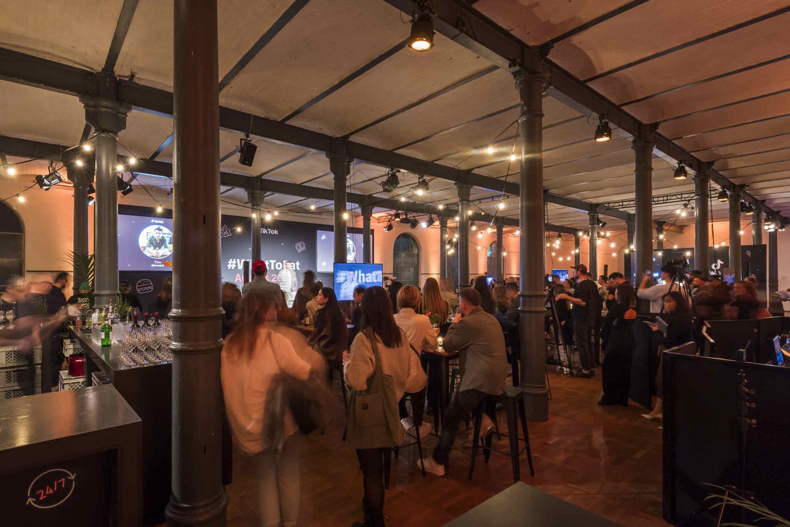 Eventsaal mit atmosphärischer Beleuchtung und Menschen während einer Veranstaltung.