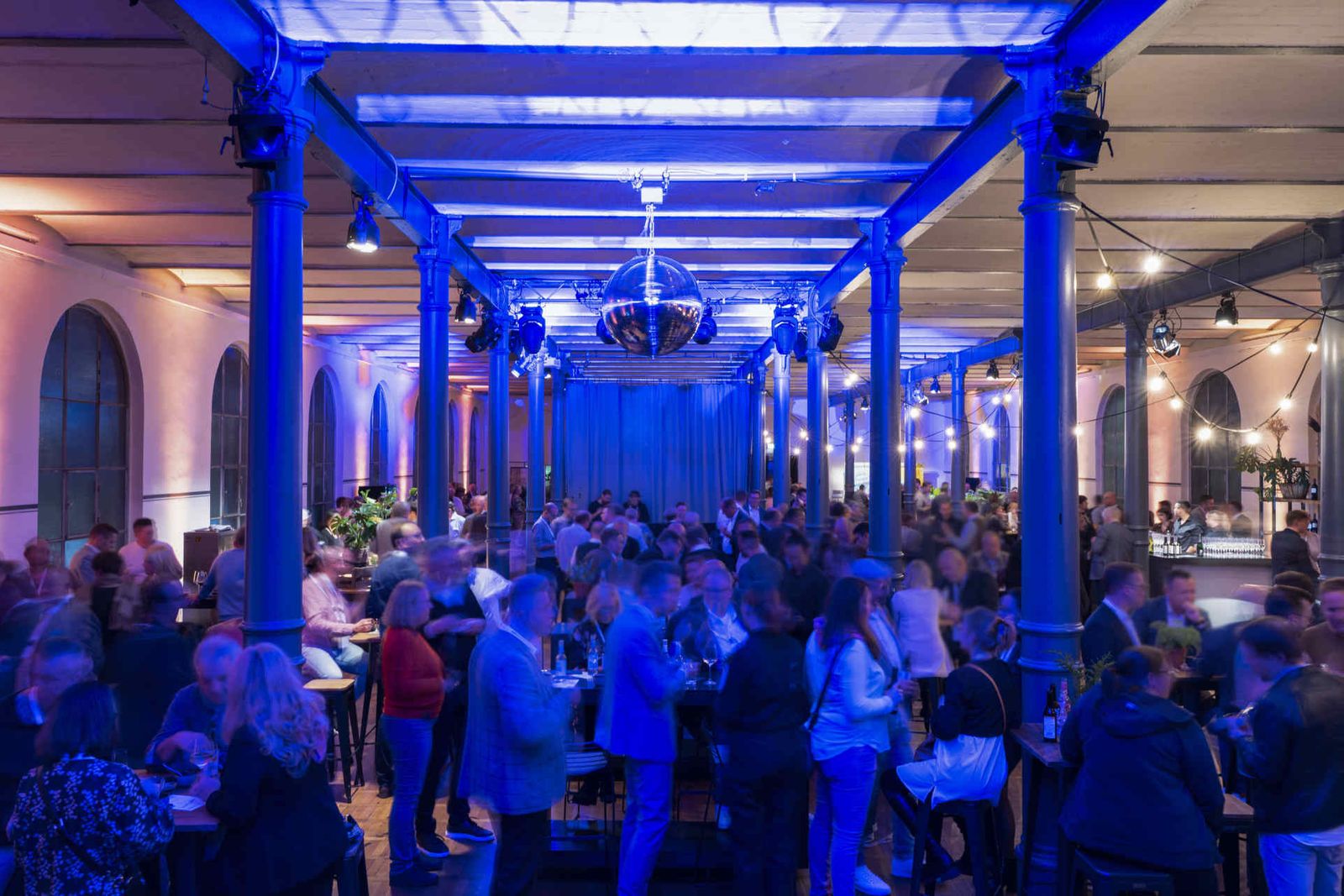 Eventsaal mit atmosphärischer Beleuchtung und Menschen während einer Veranstaltung.