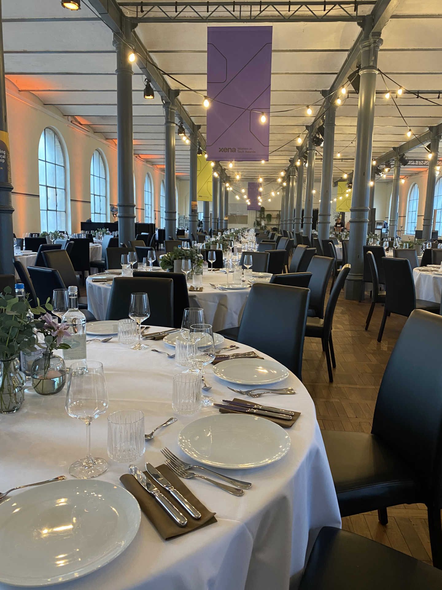 Festsaal mit runden gedeckten Dinnertischen mit weißen Tischdecken