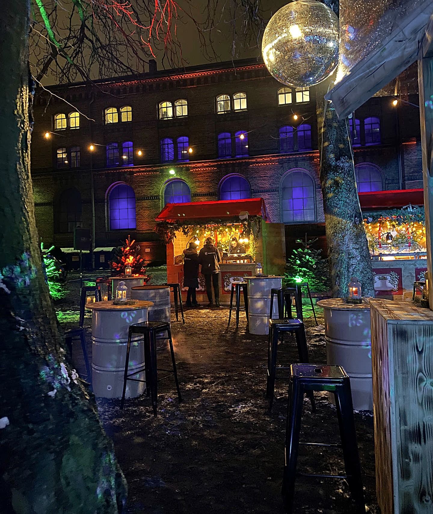 Weihnachtsfeier Location Berlin – winterlicher Courtyard der Heeresbäckerei mit Discokugel und Fassmöbeln bei Nacht