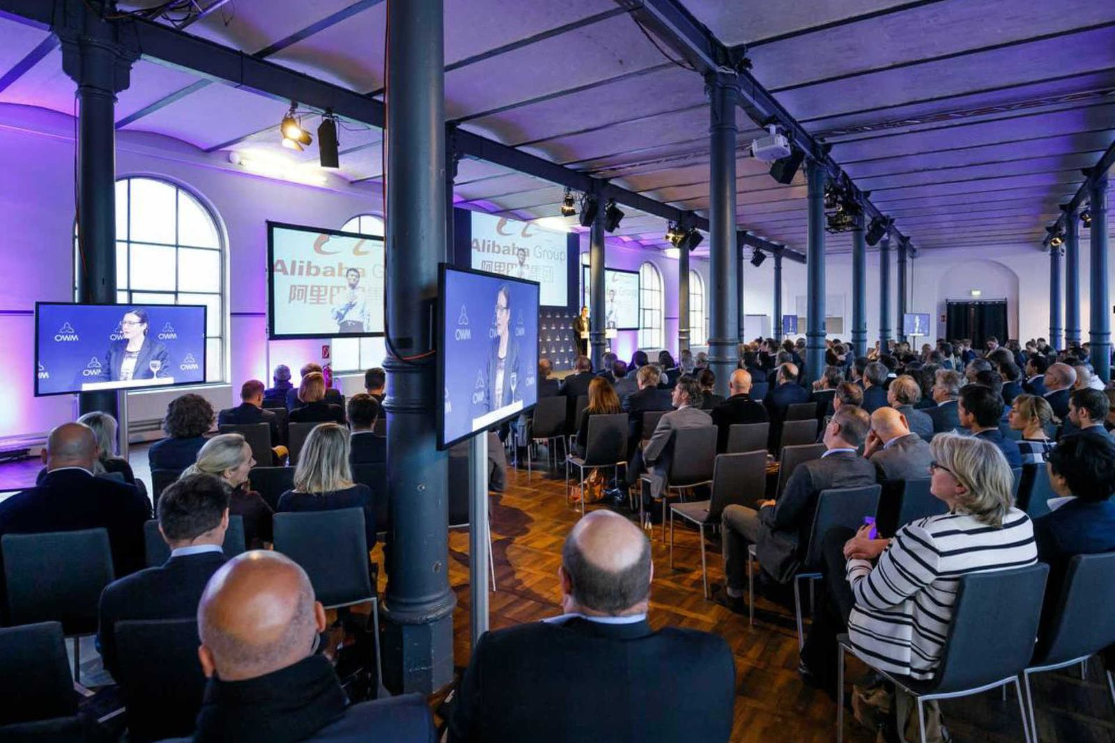 Großer Saal mit vielen Menschen in Konferenzbestuhlung und vielen Bildschirmen