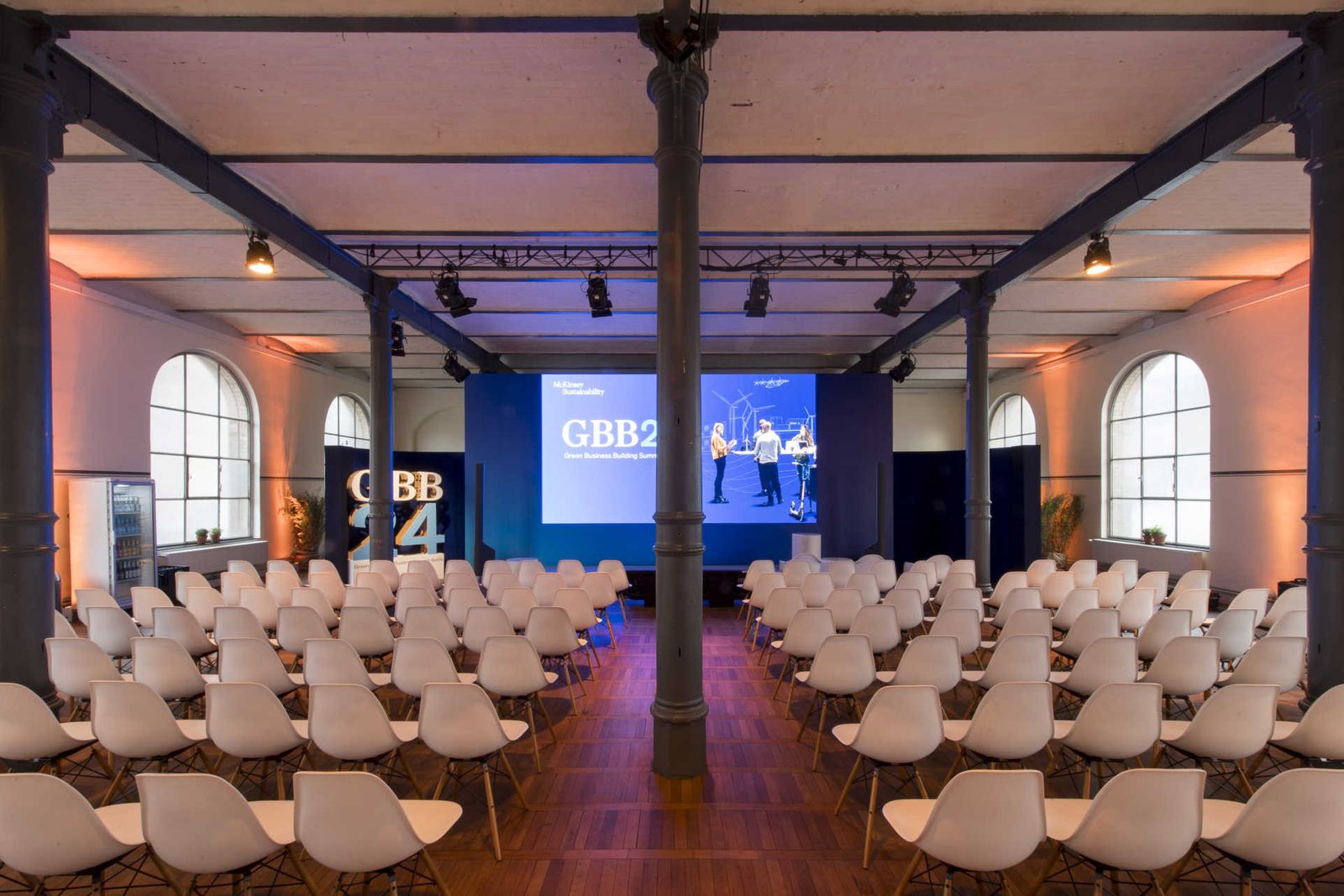 Reihenbestuhlung vor einer Bühne im Saal.