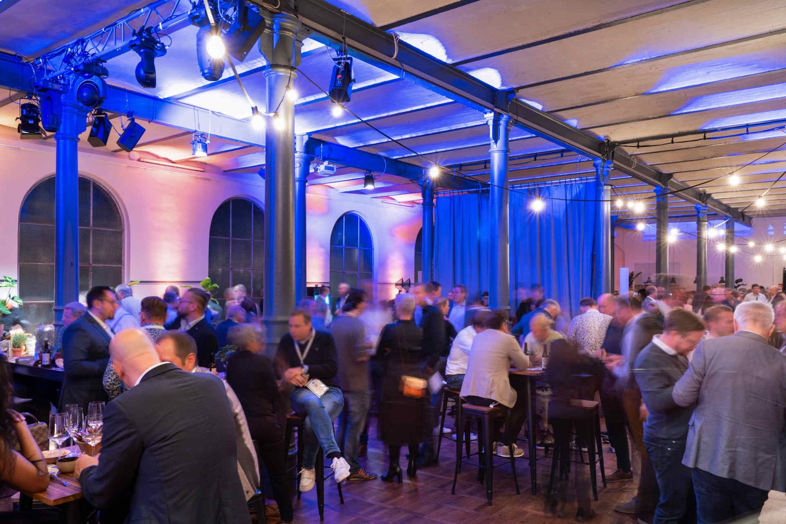 Eventsaal mit atmosphärischer Beleuchtung und Menschen während einer Veranstaltung.