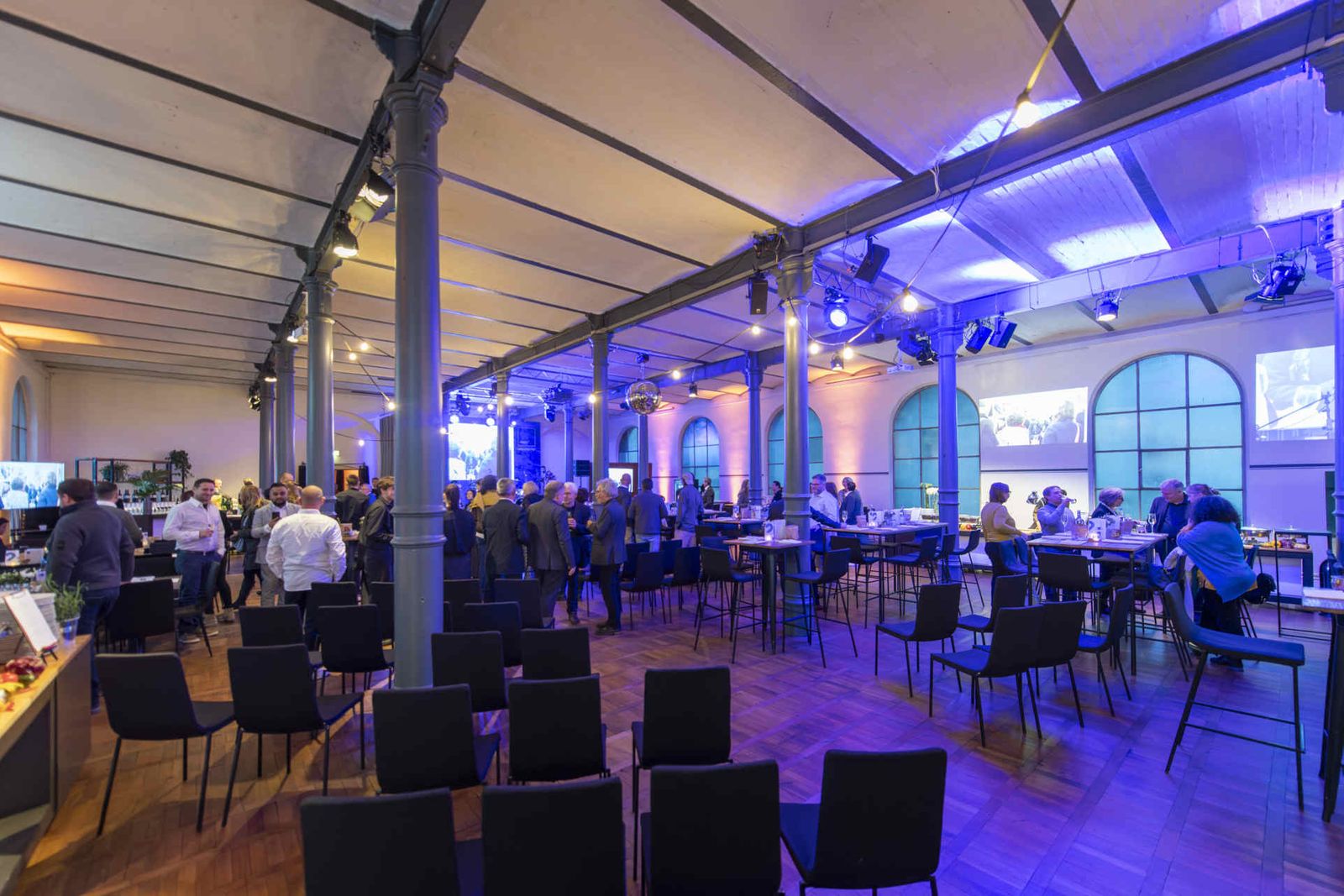 Eventsaal mit atmosphärischer Beleuchtung und Menschen während einer Veranstaltung.