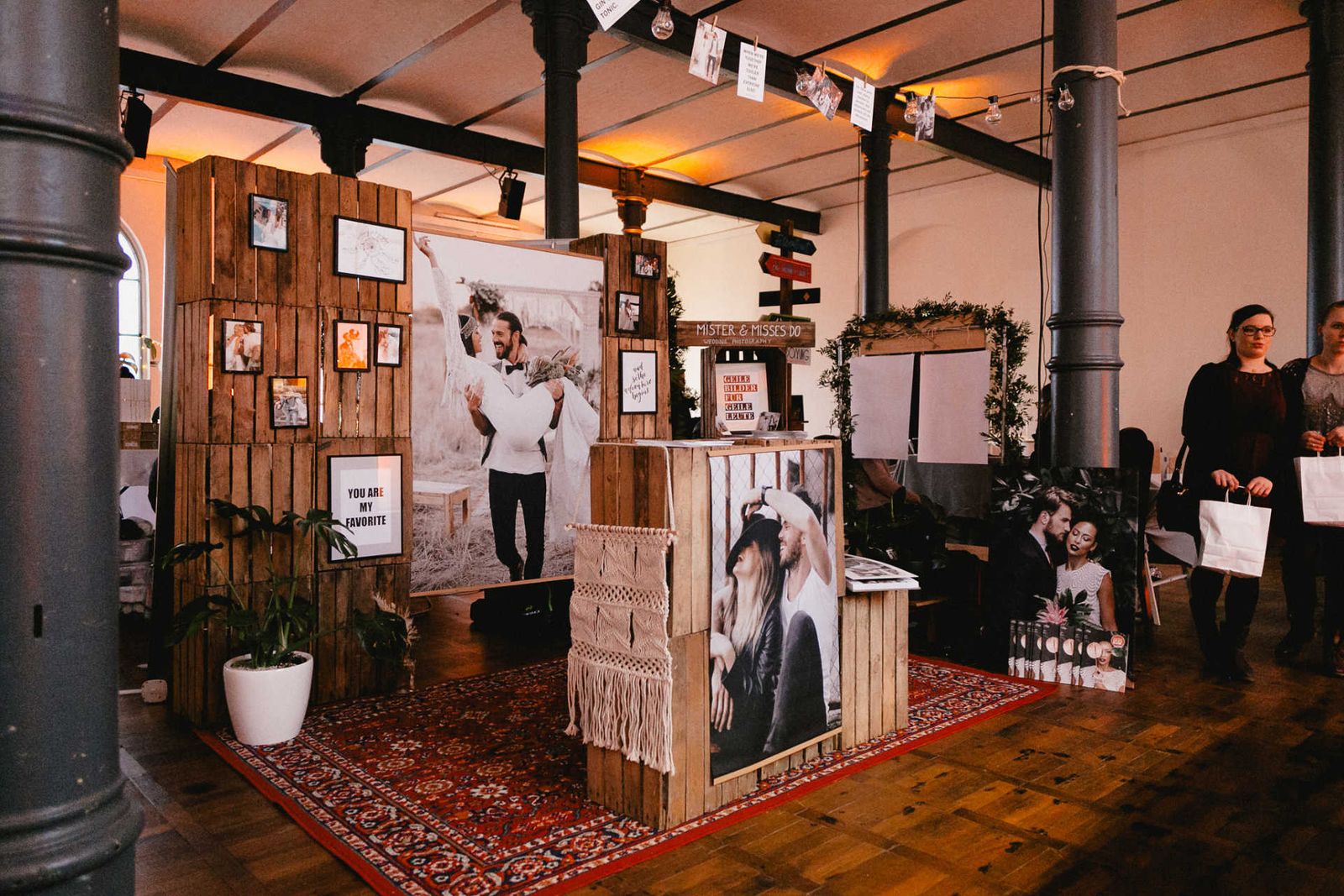 Exhibition area of a wedding fair with Persian carpet and wooden crates in boho style.